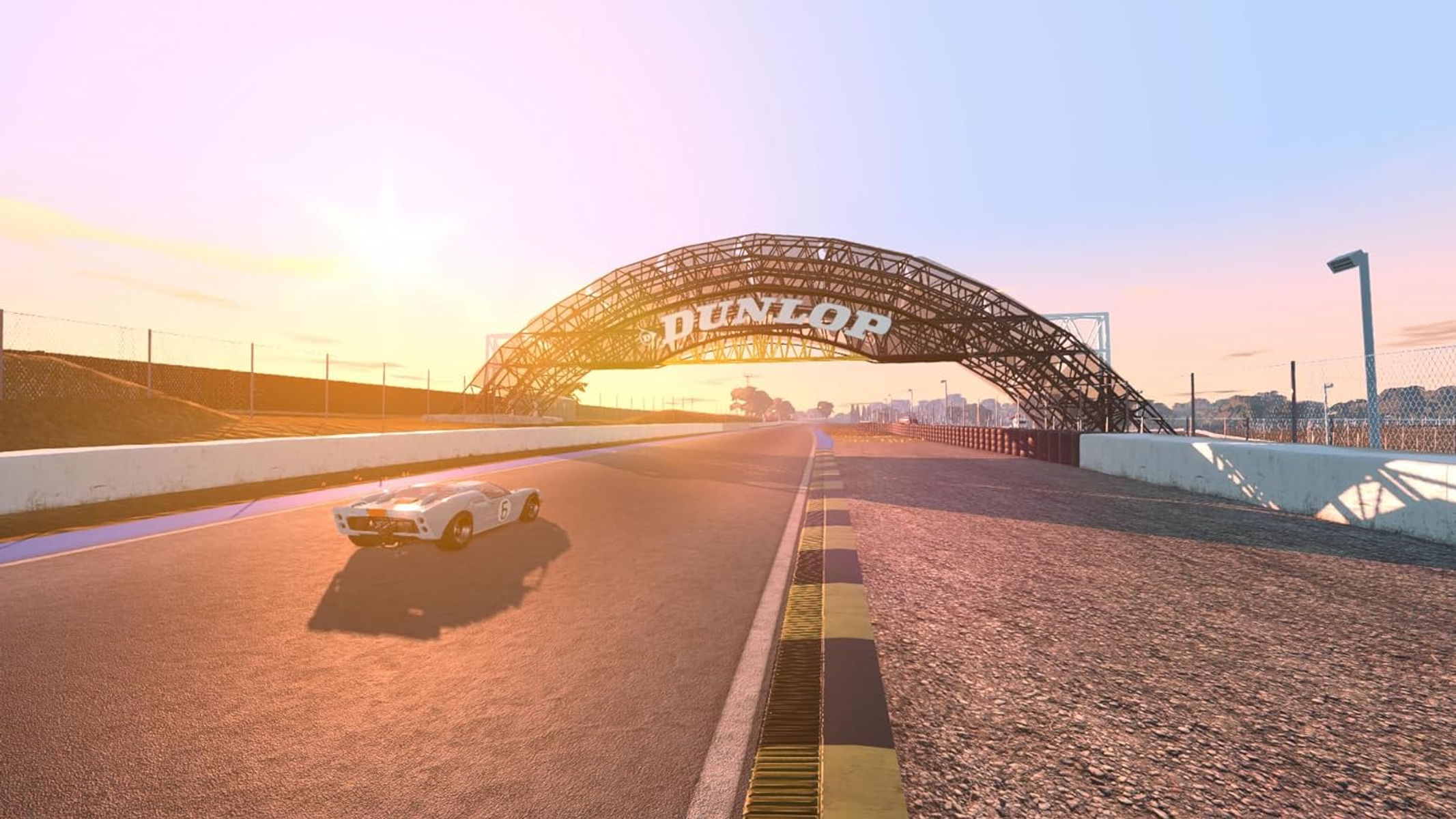 Un'auto da corsa su una pista, che si avvicina a un arco Dunlop al tramonto. Il cielo è arancione.