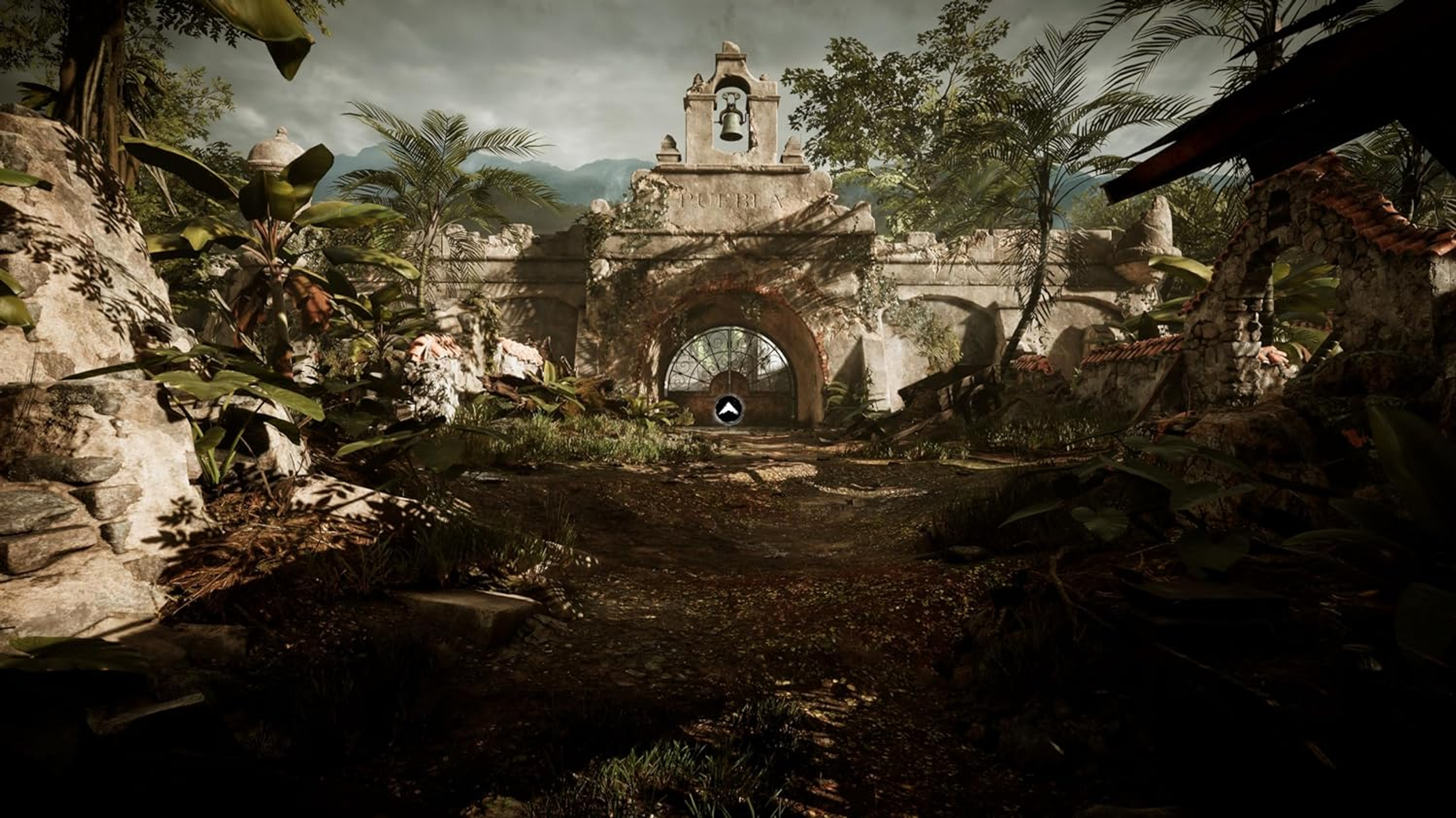 Stara kamienna brama z dzwonnicą i bujną zieloną roślinnością.