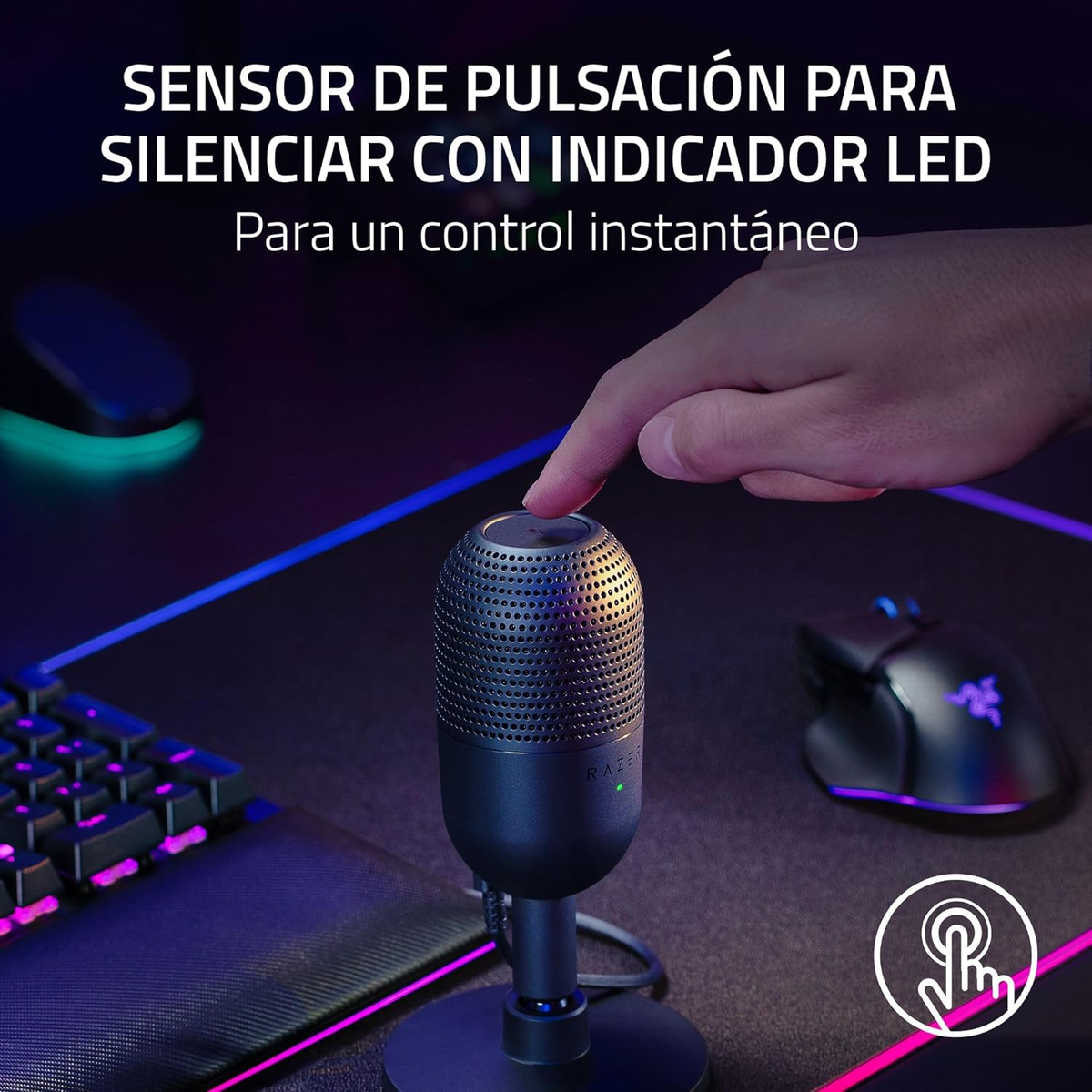 Una mano preme un pulsante su un microfono Razer nero su una scrivania con tastiera e mouse.