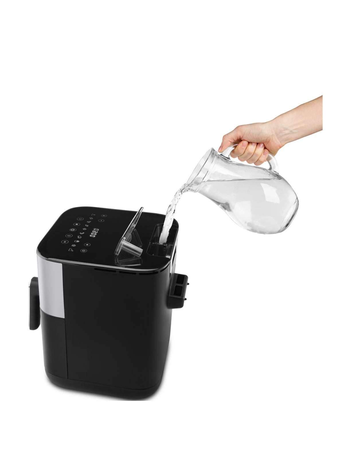 Ręka wlewa wodę do czarnej frytownicy beztłuszczowej na białym tle.