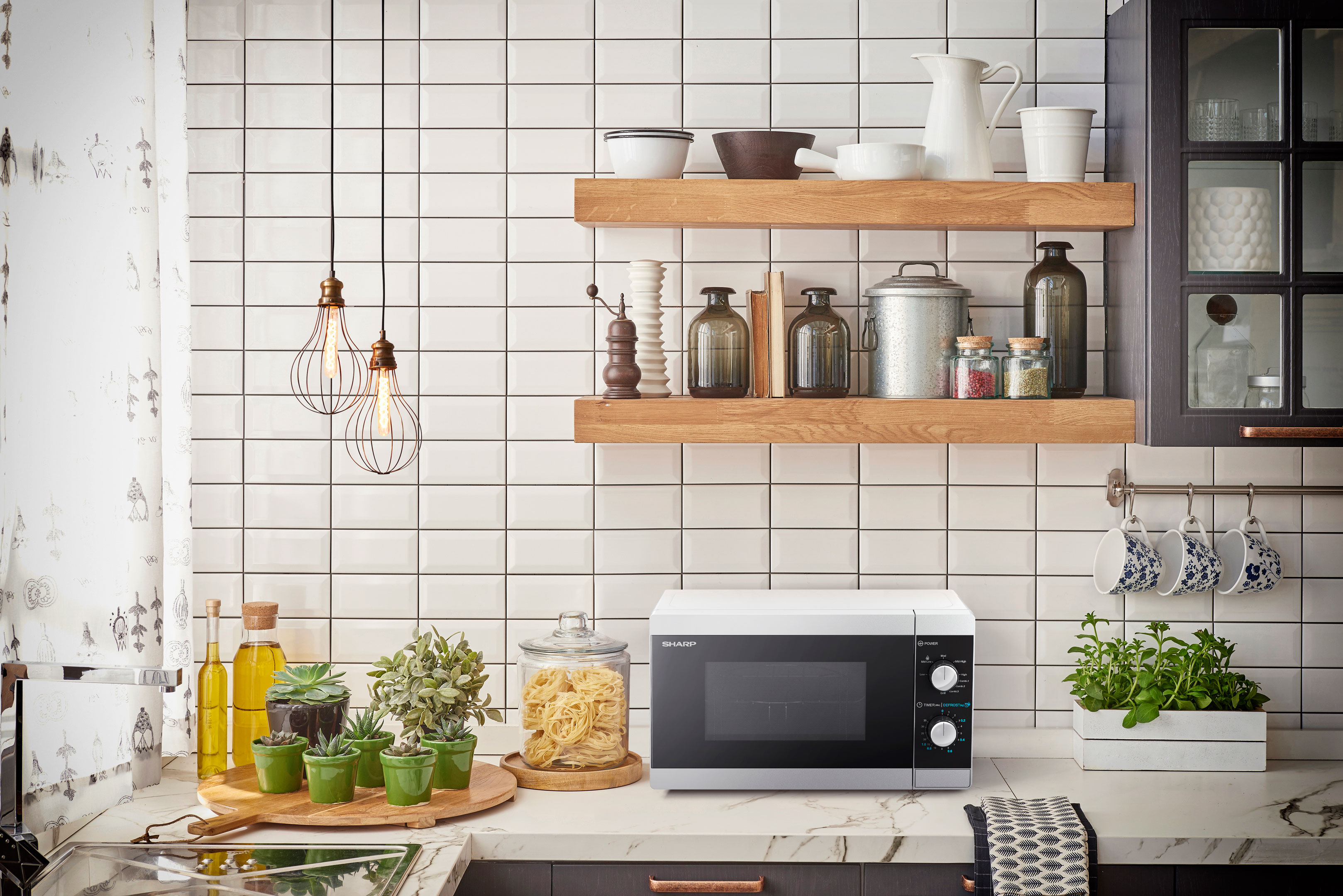 Kuchenka mikrofalowa na blacie kuchennym, z elementami dekoracyjnymi i białym tłem z płytek.