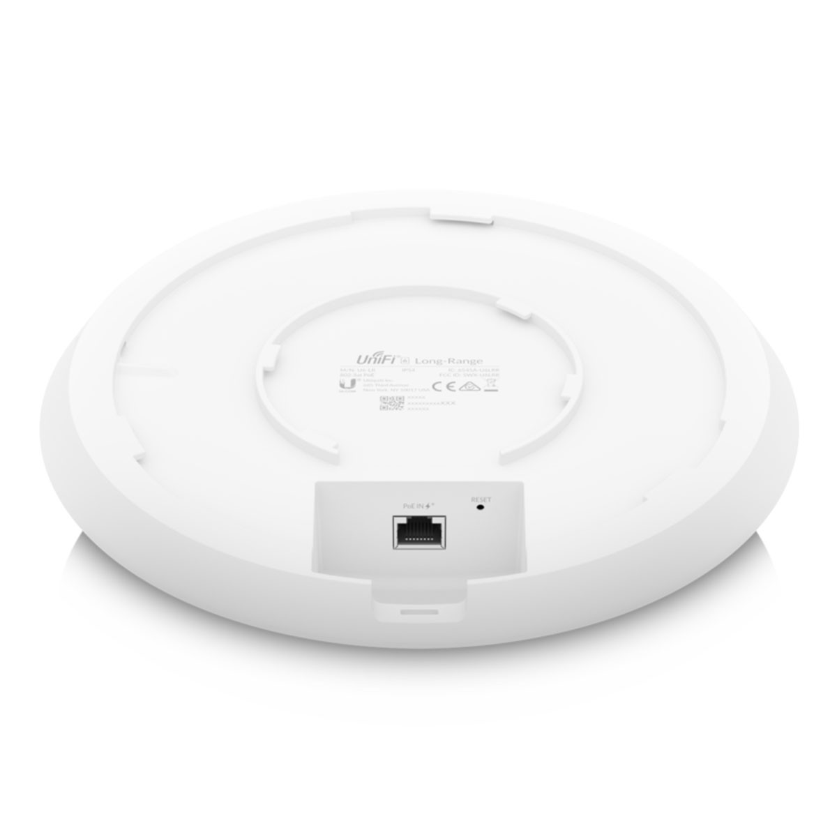 Białe, okrągłe urządzenie z portem i przyciskiem reset, widok od spodu, na białym tle.