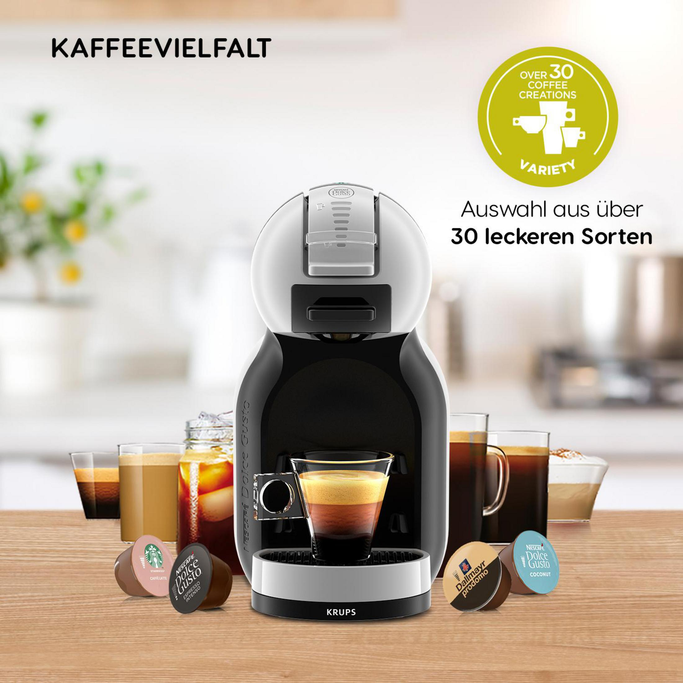 Eine Kaffeemaschine mit Kaffeekapseln und Tassen. Sie hat ein weißes und schwarzes Design mit dem Text 'KAFFEEVIELFALT'.