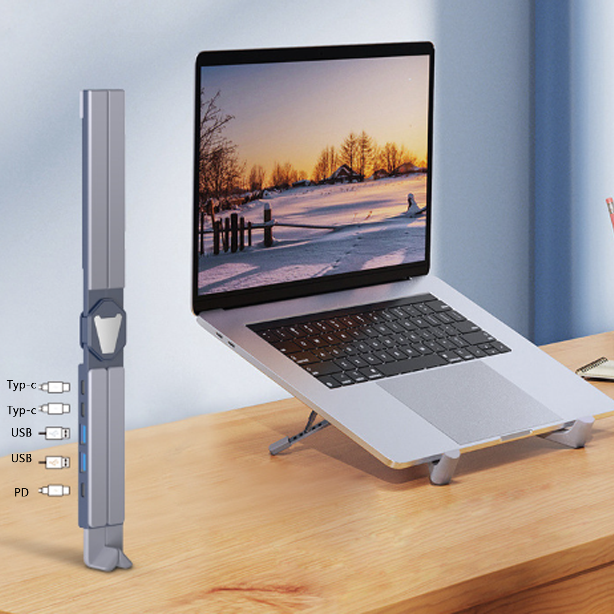 Ein grauer Laptop-Ständer und ein silberner Laptop mit Anschlüssen und einem USB-Hub auf einem Holzschreibtisch.