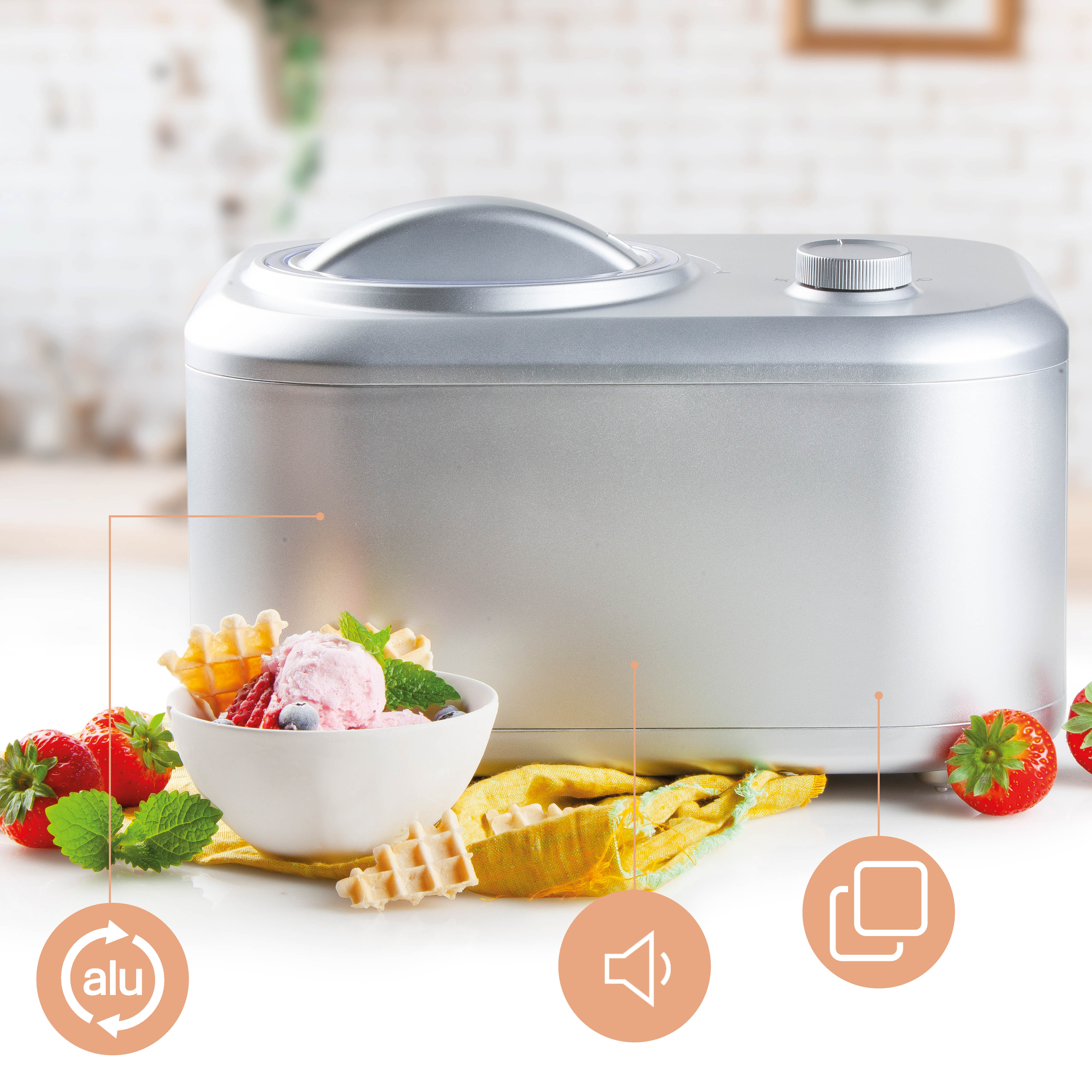Silver ice cream maker with bowl of ice cream and strawberries. White table, yellow cloth.