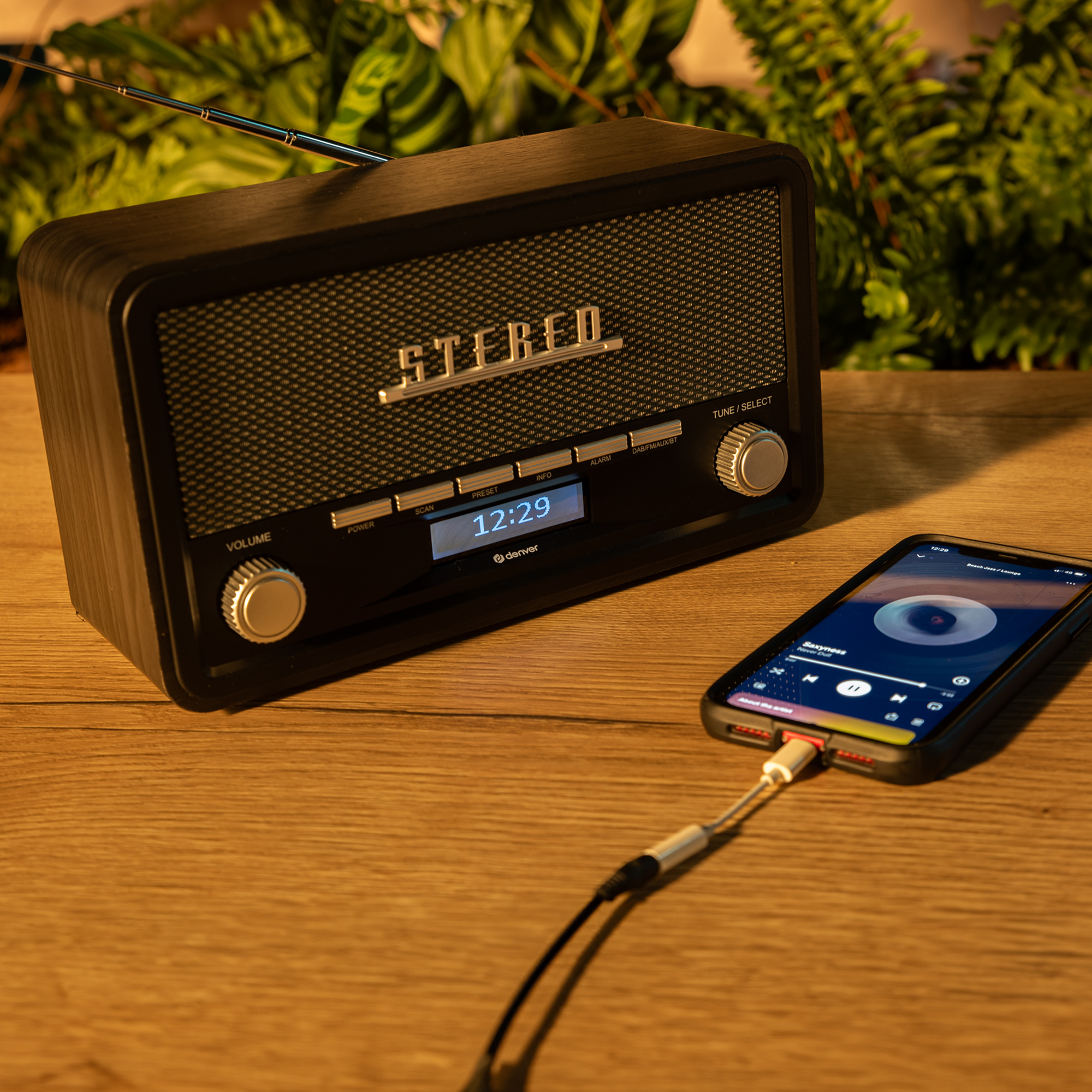 Radio w stylu vintage z podłączonym telefonem. Radio jest ciemne, a telefon pokazuje interfejs muzyczny.