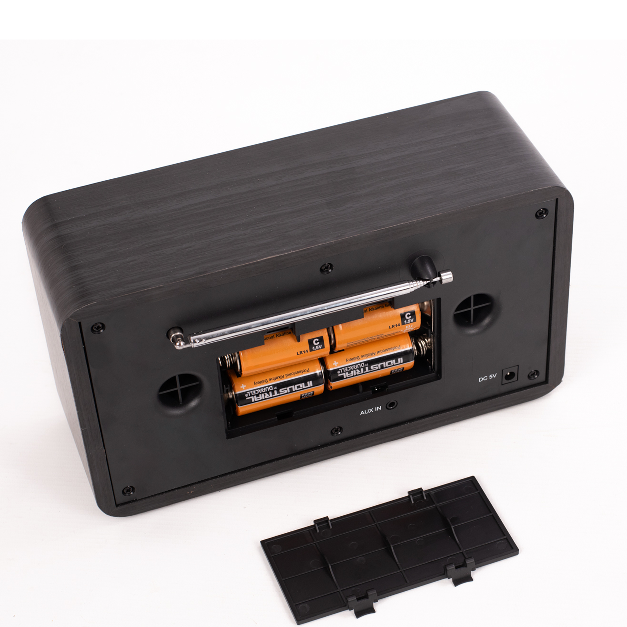 Tył czarnego drewnianego radia z otwartą komorą baterii i bateriami w środku.