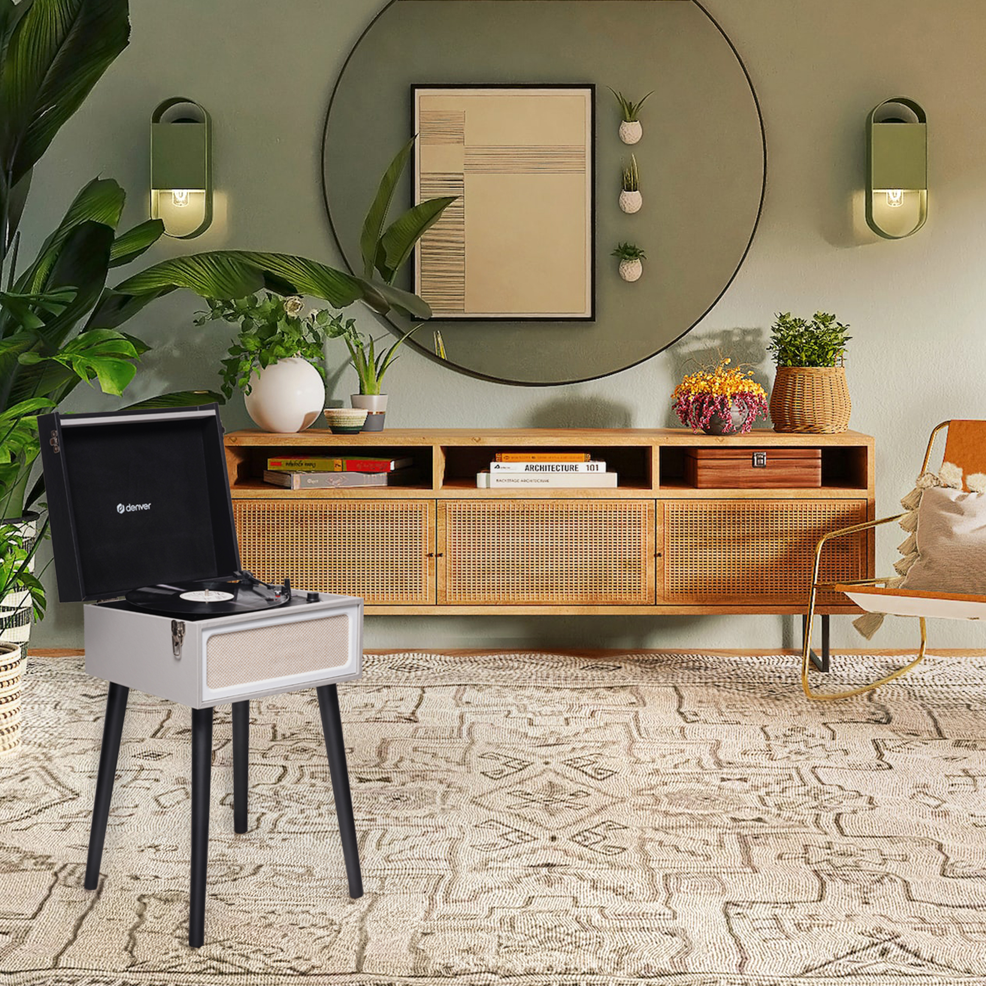 Gramofon przed ścianą z lustrem i roślinami. Widoczny dywan i fotel.