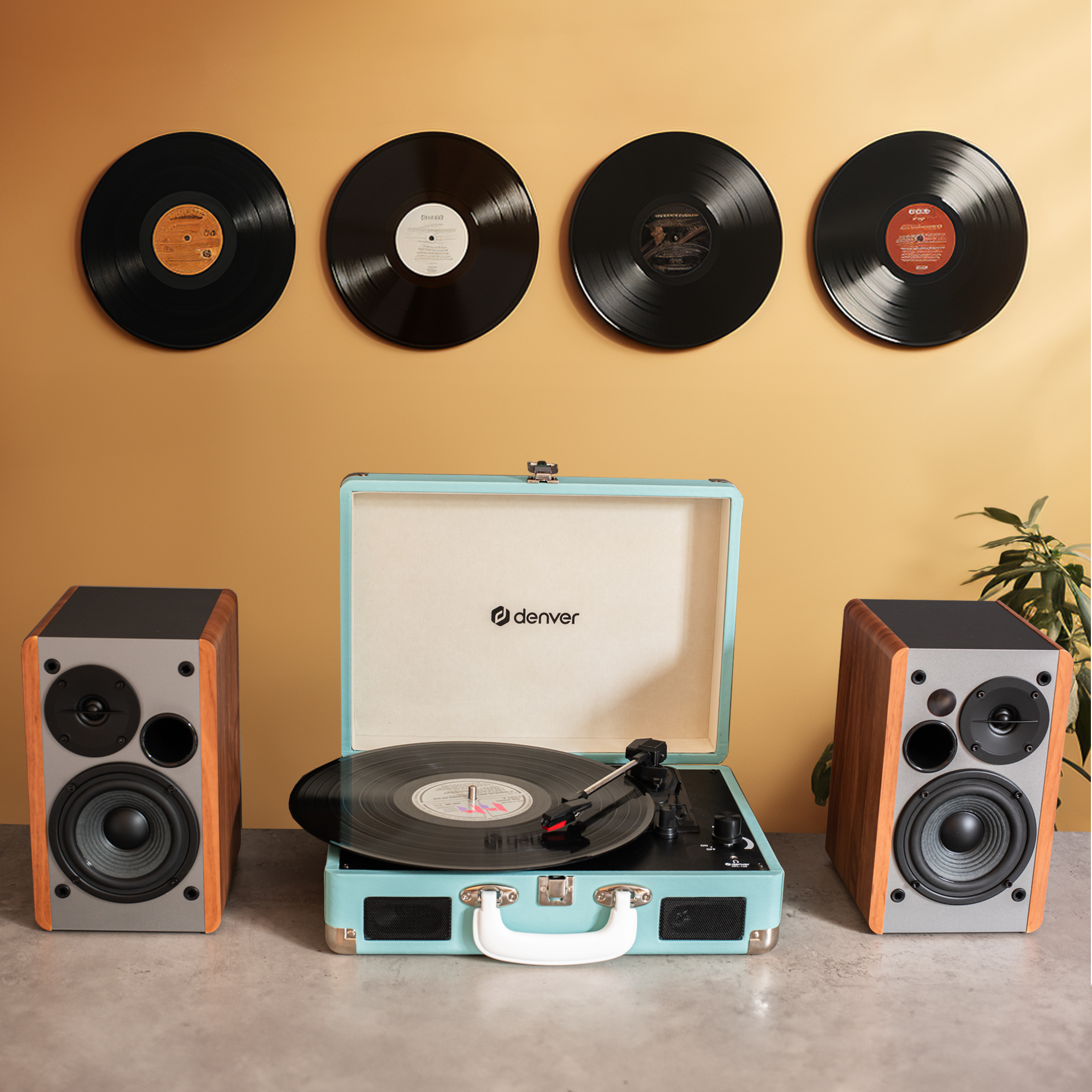 Tocadiscos con discos y altavoces en una mesa, con discos en la pared al fondo.