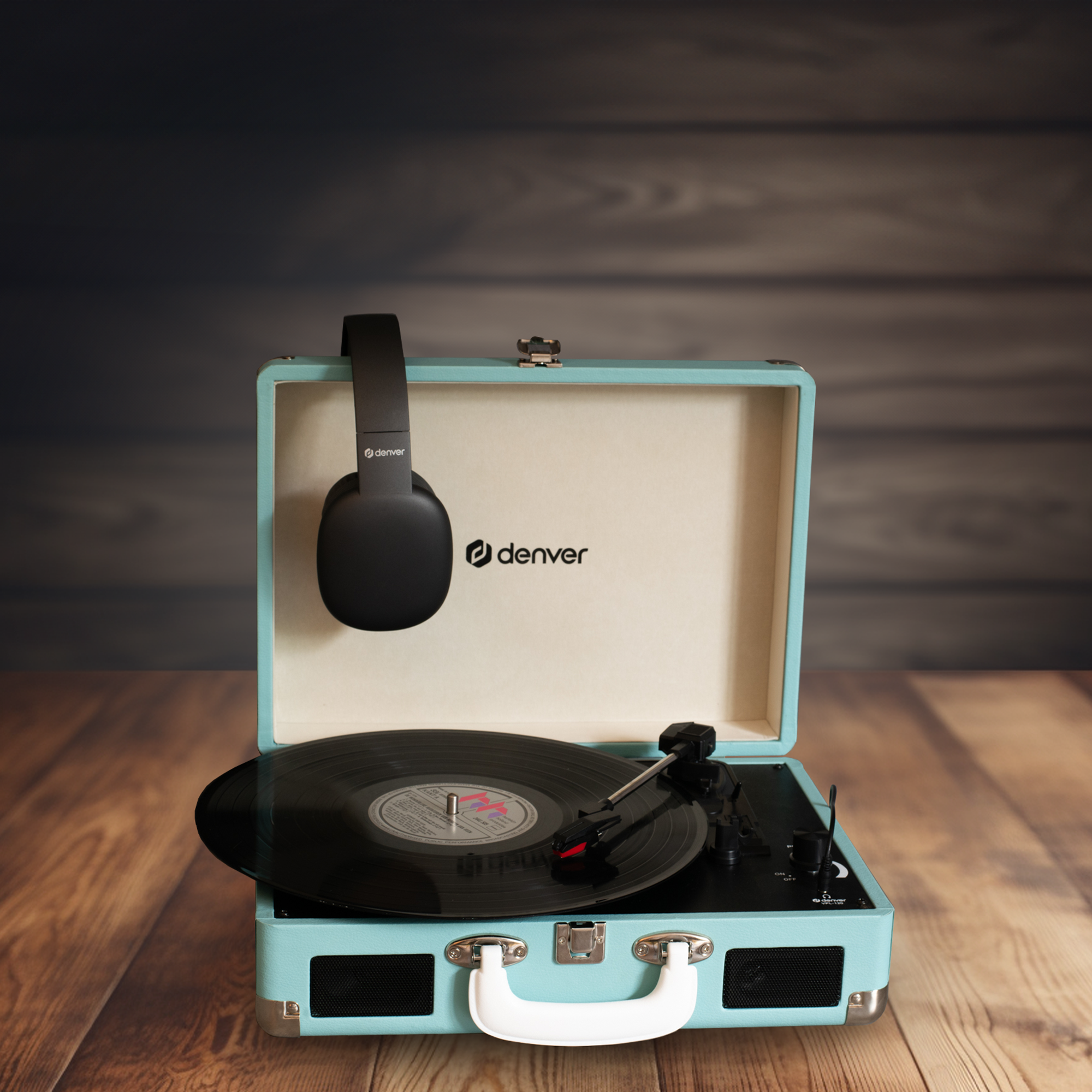 Un tocadiscos turquesa con un disco de vinilo negro y auriculares. Está sobre una mesa de madera.