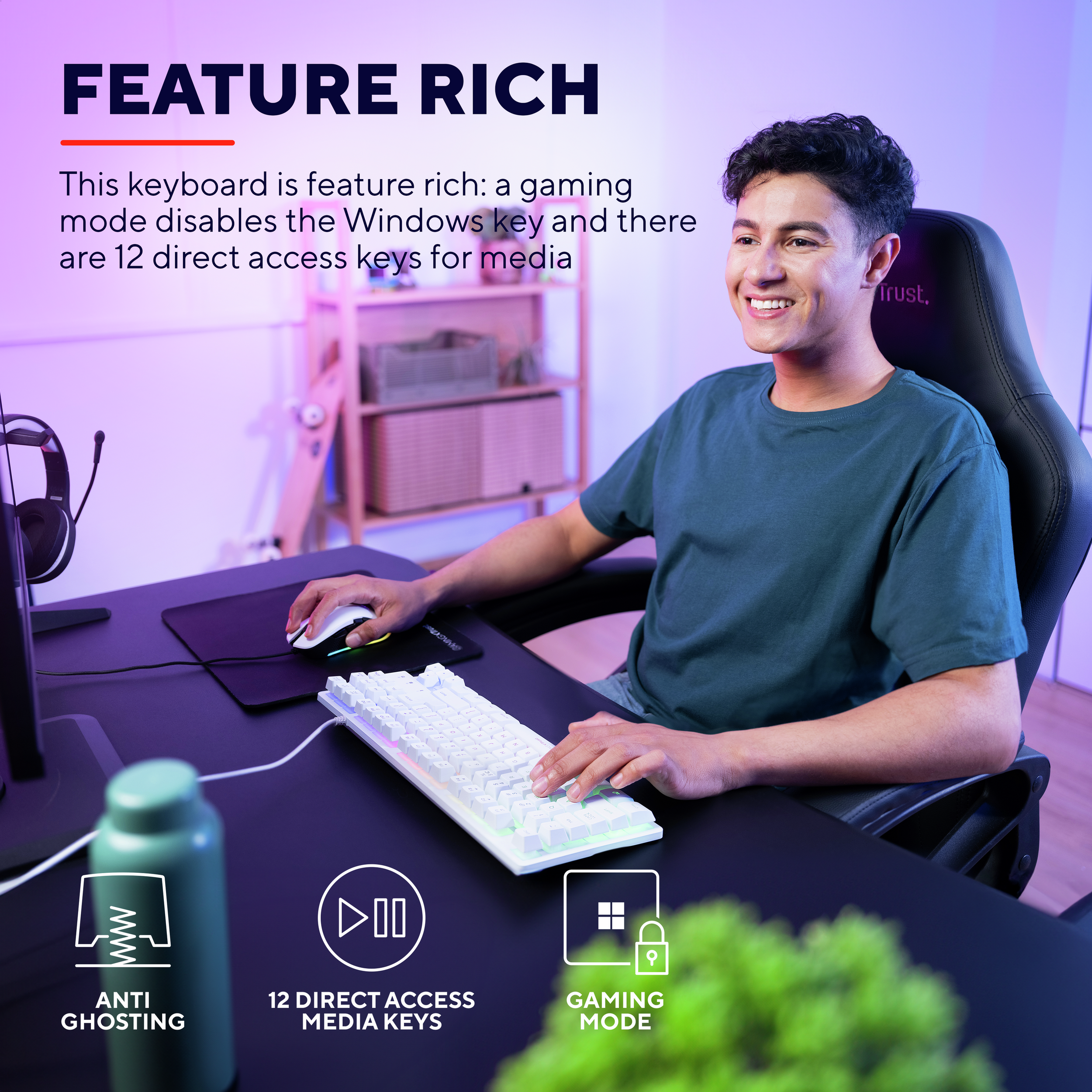 Mann lächelt am Keyboard. Schreibtisch mit Tastatur, Maus und Wasserflasche. Gaming-Modus und Medientasten hervorgehoben.