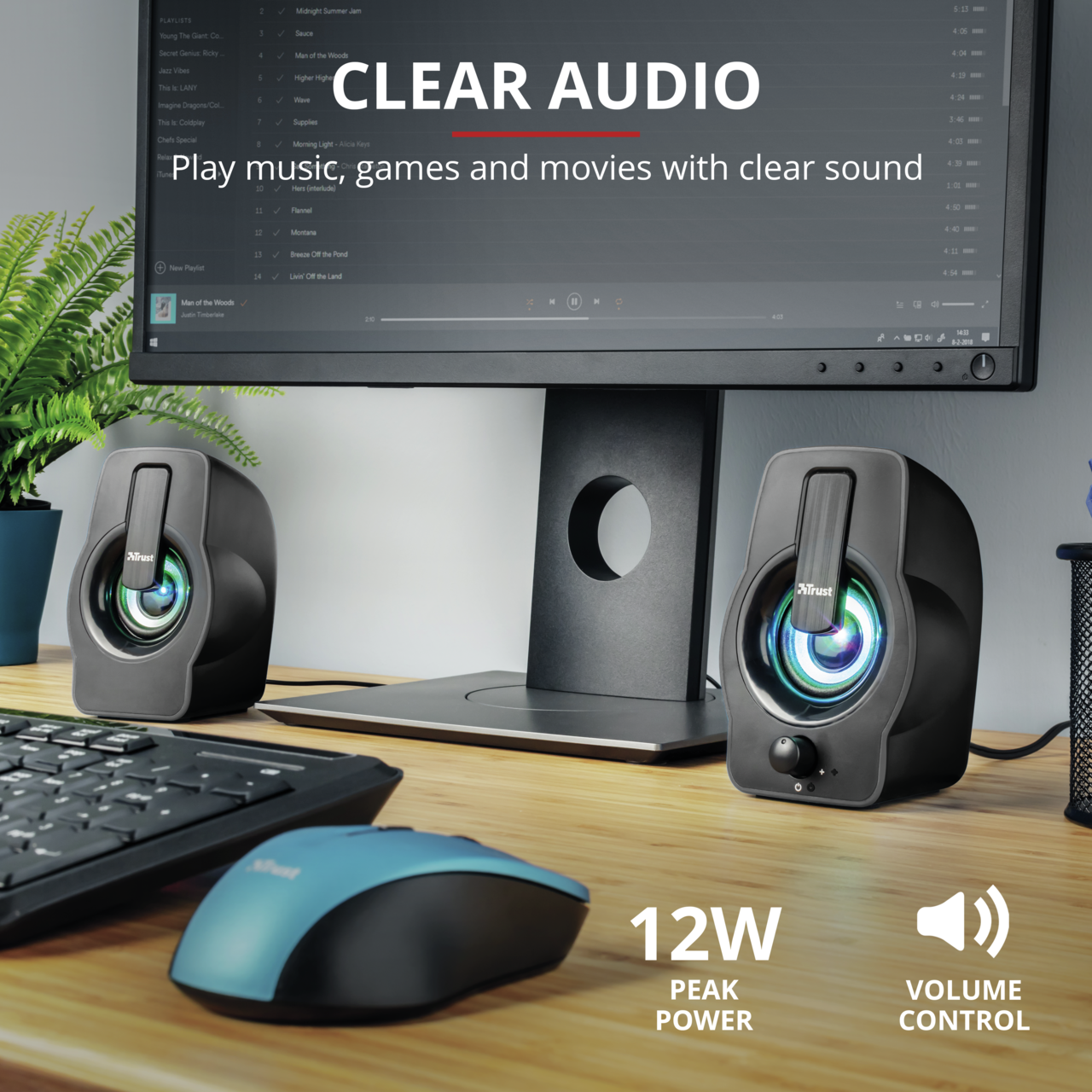 Two black computer speakers with a computer monitor, keyboard and mouse on a desk.