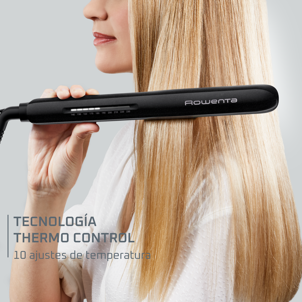 Woman using a black hair straightener with temperature settings visible.
