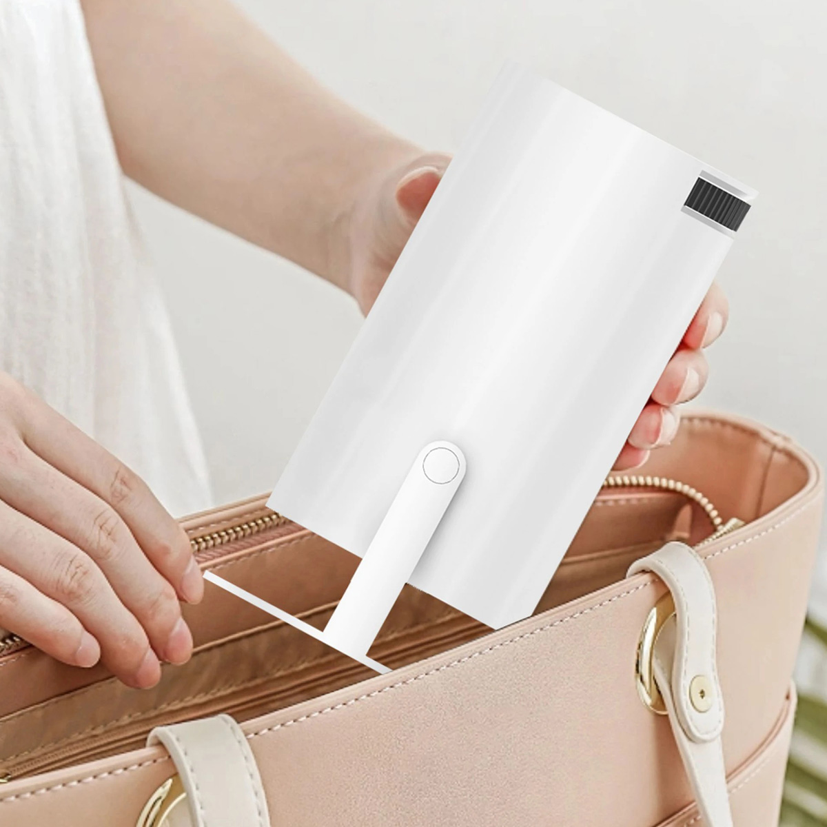 Una impresora negra, un adaptador de corriente, un cable USB y un cable de alimentación están sobre una superficie blanca.
