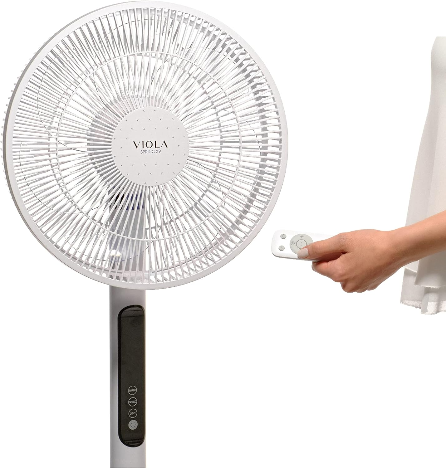 Un ventilador de pie blanco con una persona sosteniendo un control remoto.