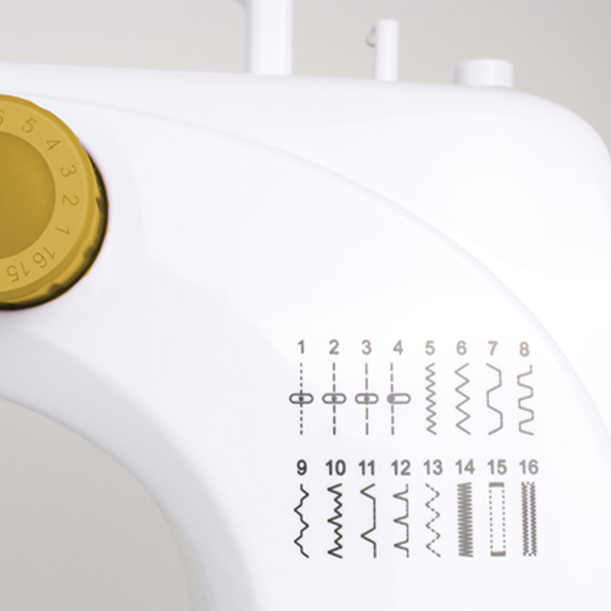 Zbliżenie białej maszyny do szycia pokazujące pokrętło wyboru ściegów i wzory ściegów.