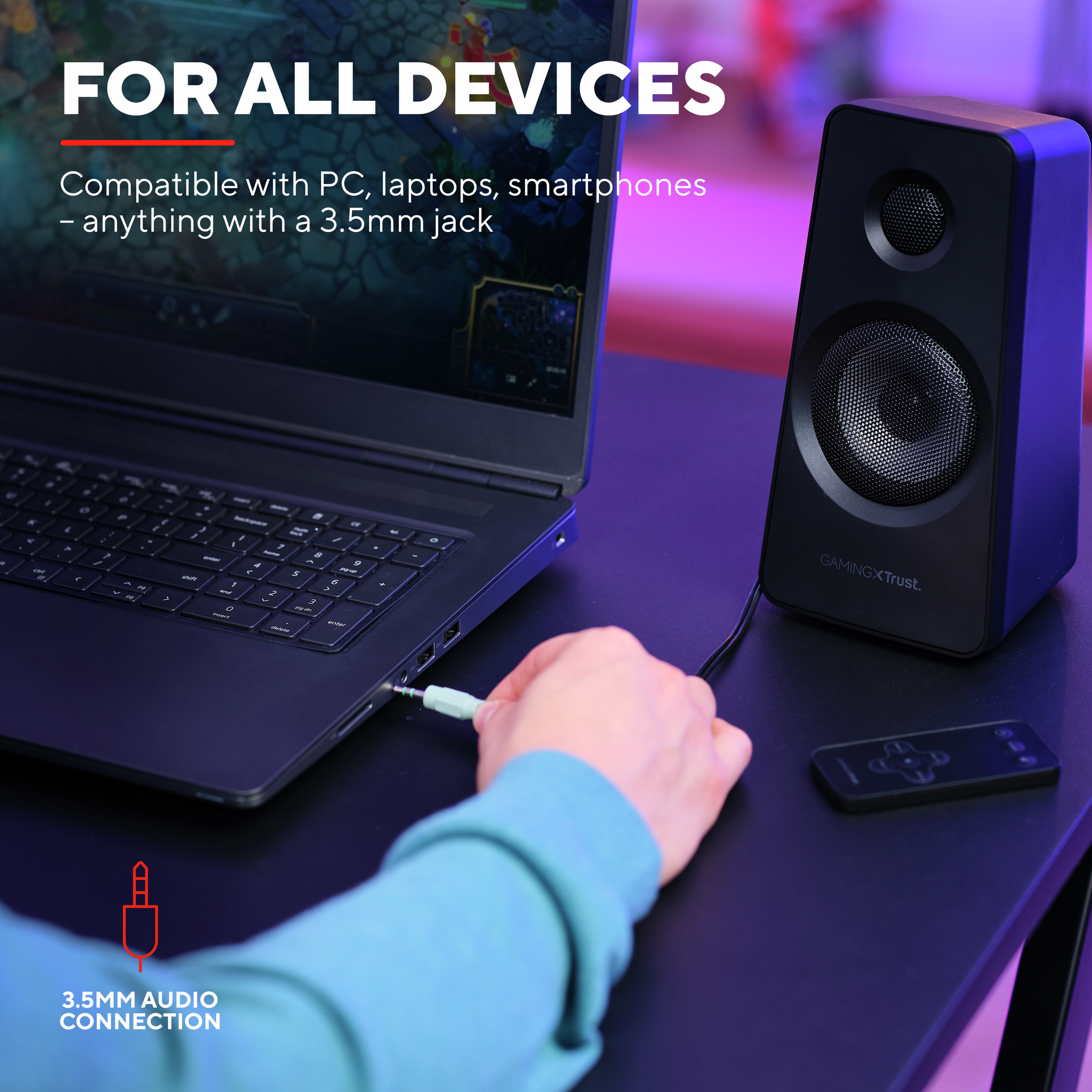 Laptop podłączony do głośnika kablem. Dłoń trzyma wtyk audio. Tekst: DLA WSZYSTKICH URZĄDZEŃ.