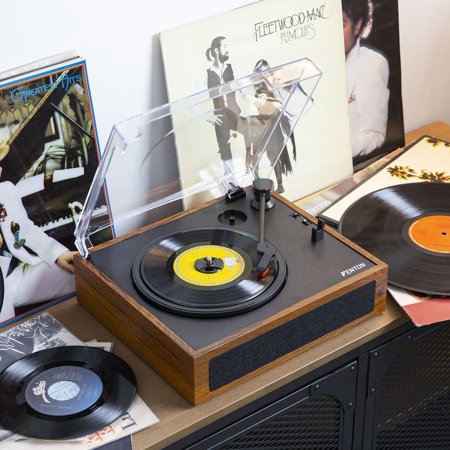 A record player with records and album covers on a wooden table.
