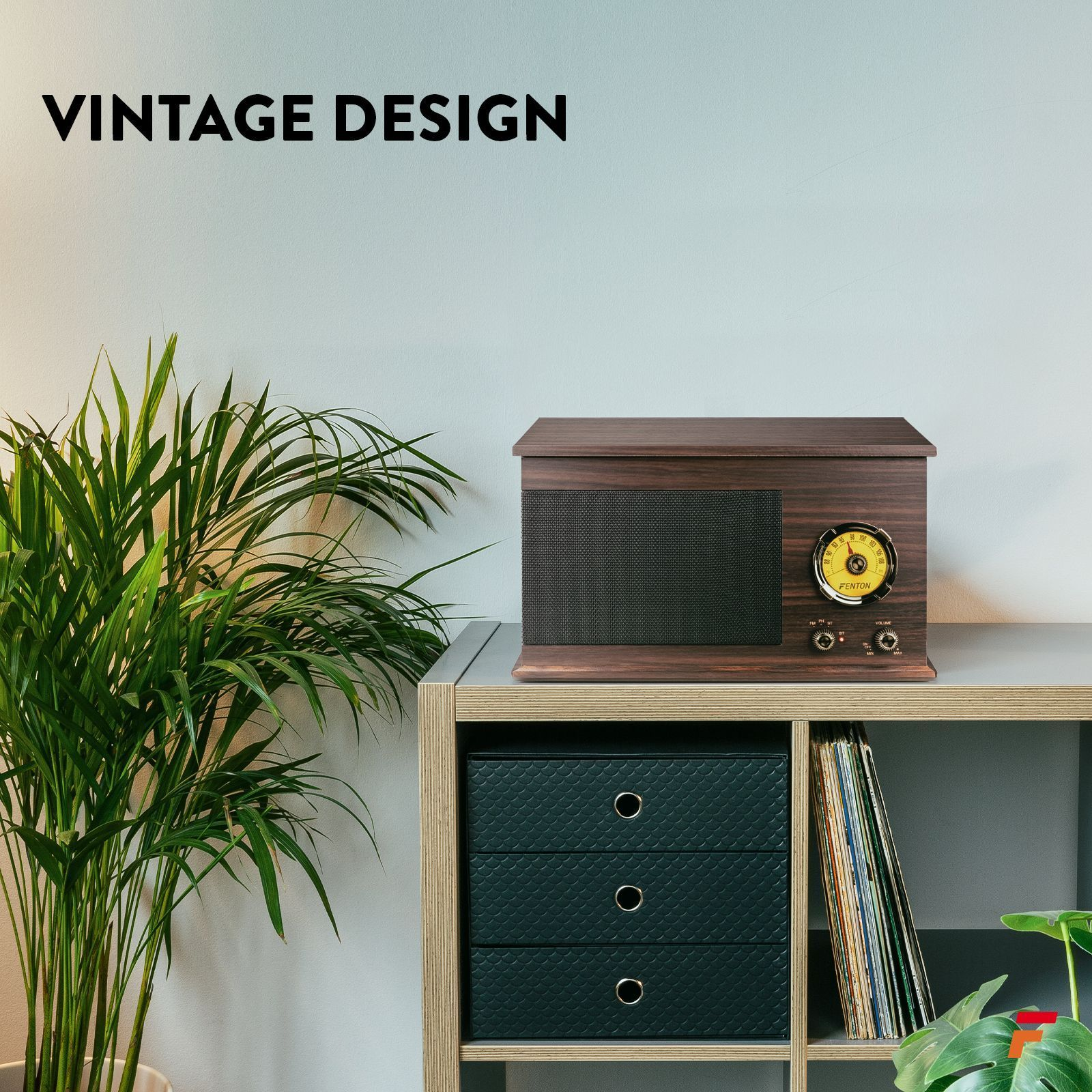 Une radio en bois de style vintage sur une étagère, avec une plante verte et une pile de disques à proximité.
