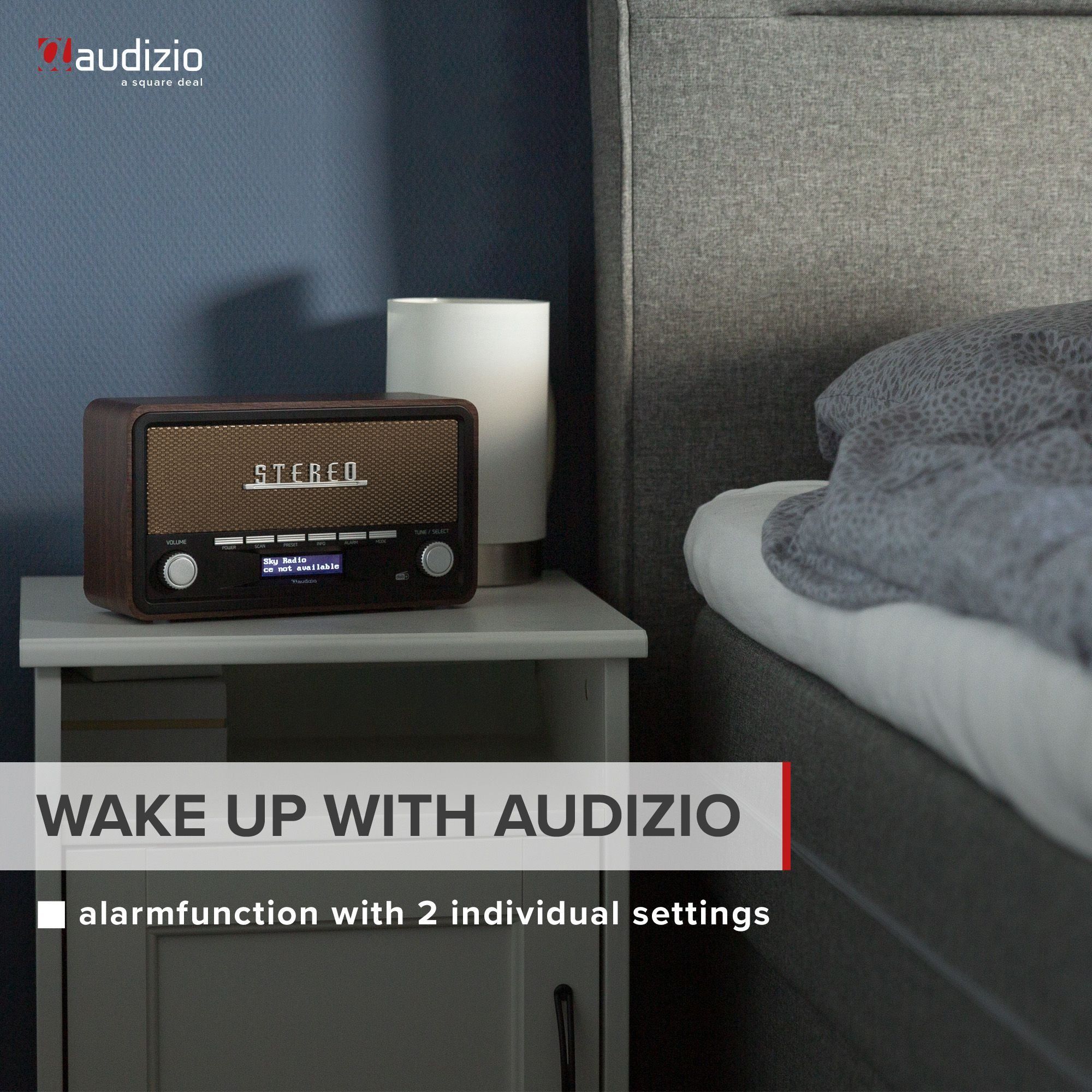 Una radio de estilo madera en una mesita de noche gris junto a una cama. Texto: Wake up with Audizio.