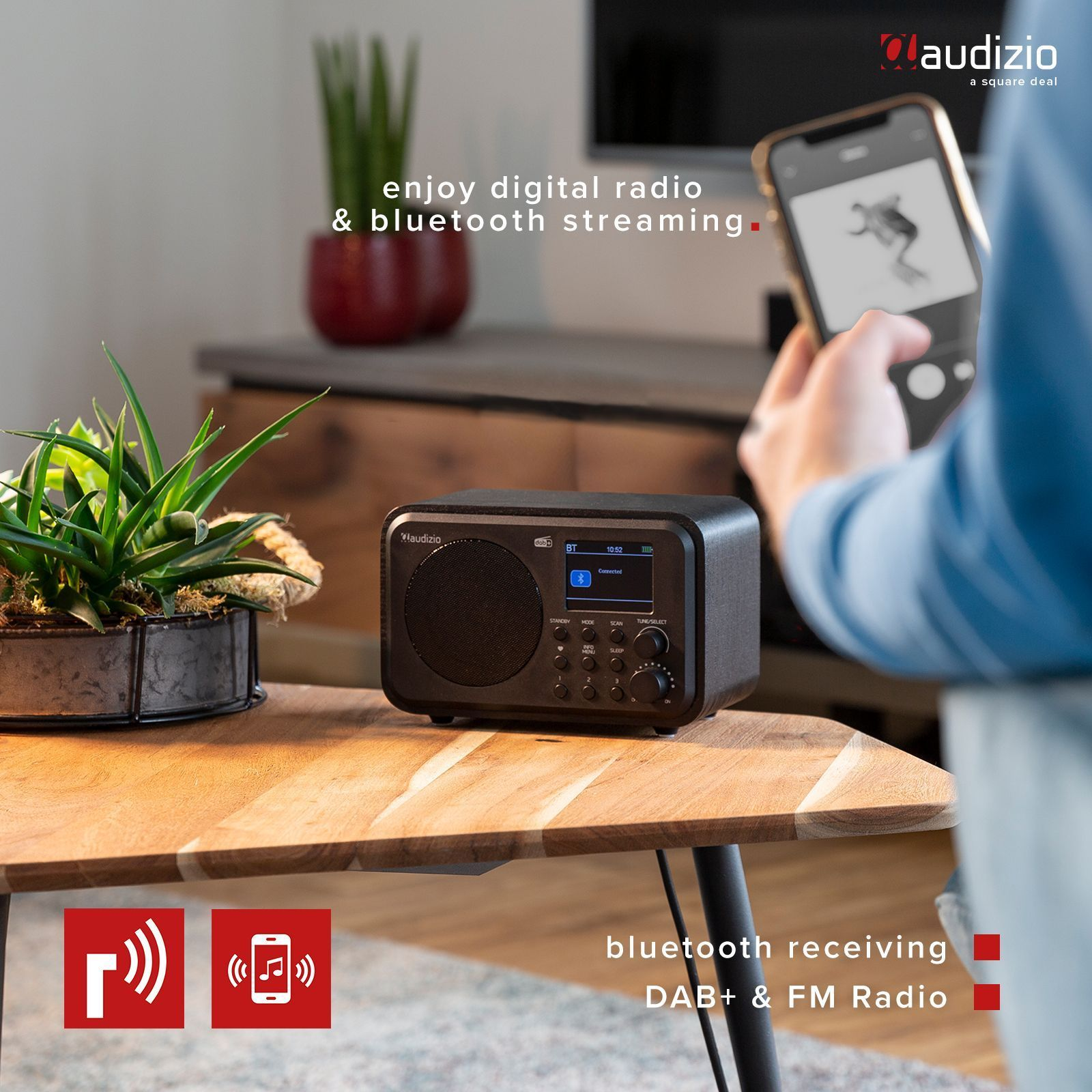 Persona usando radio digital y transmisión Bluetooth en el teléfono. Radio y planta en la mesa.