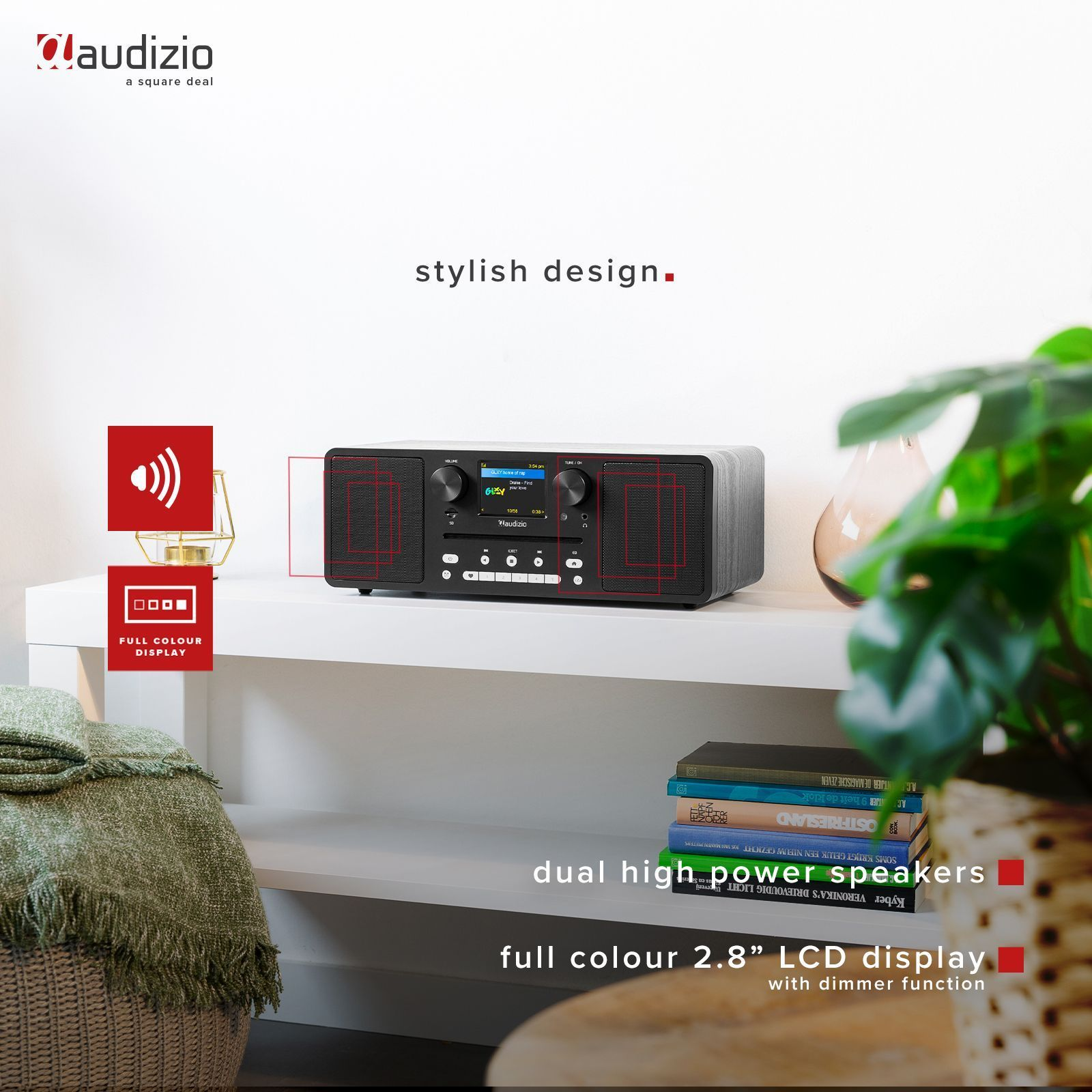Schwarze Stereoanlage mit Radio- und Lautsprecherdesign auf weißem Regal, mit Pflanze und Büchern.