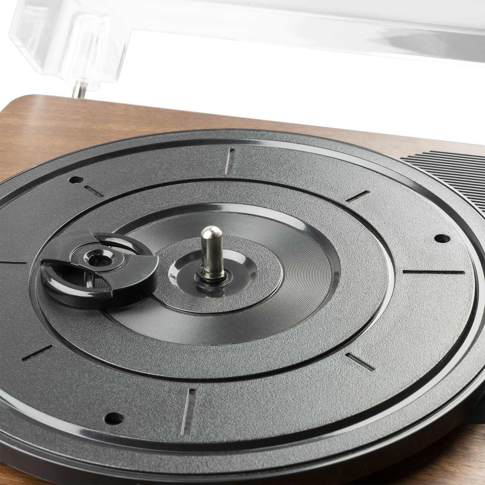 Primer plano del disco negro de un tocadiscos. El eje plateado está centrado. Cubierta transparente parcialmente visible.