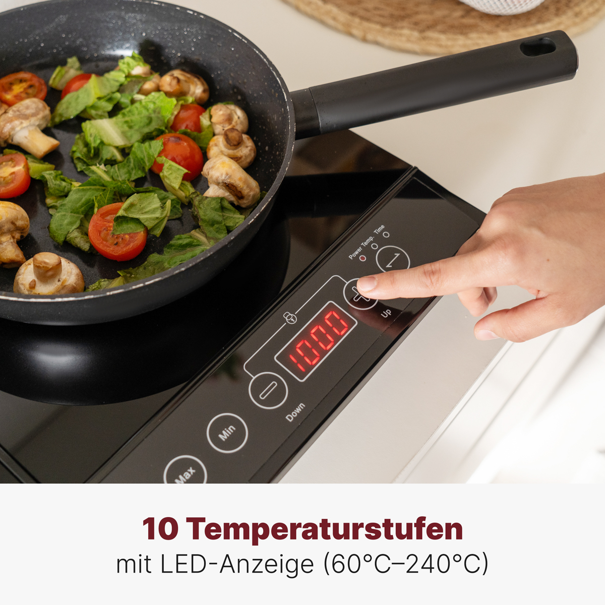 Patelnia z warzywami na płycie indukcyjnej, ręka osoby naciska przycisk.