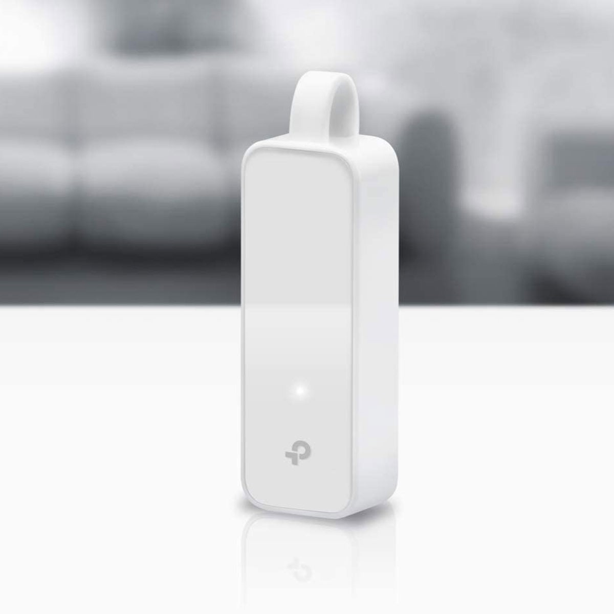 White, rectangular TP-Link device with a handle. It has a glowing light and a logo. Background is blurred.