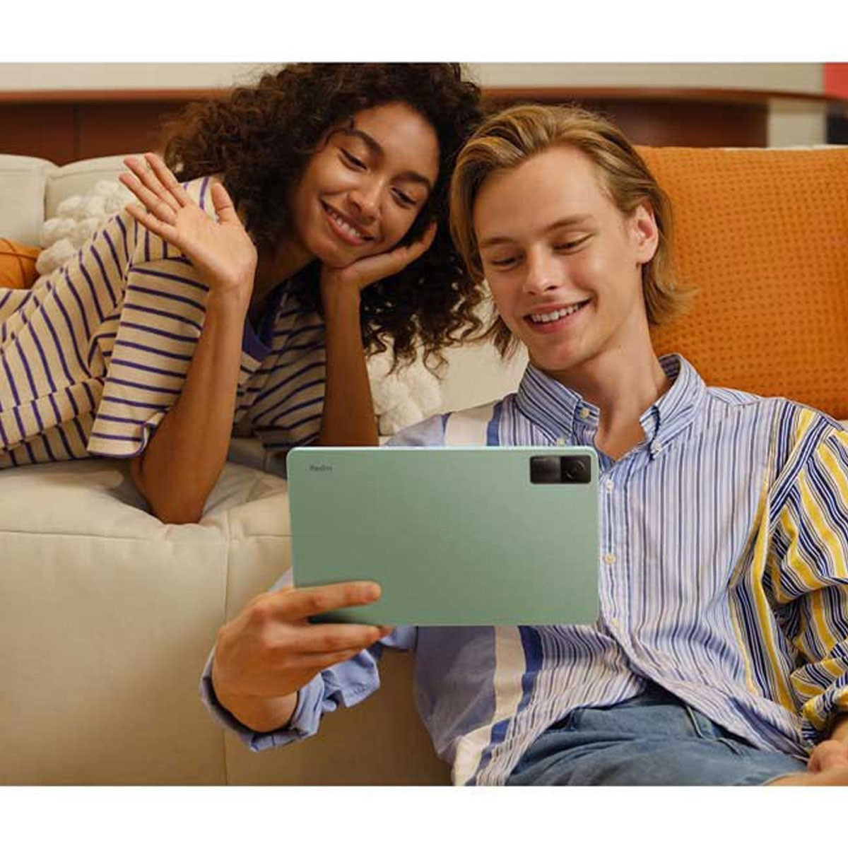 Dwie osoby na kanapie patrzące na zielony tablet z aparatem.