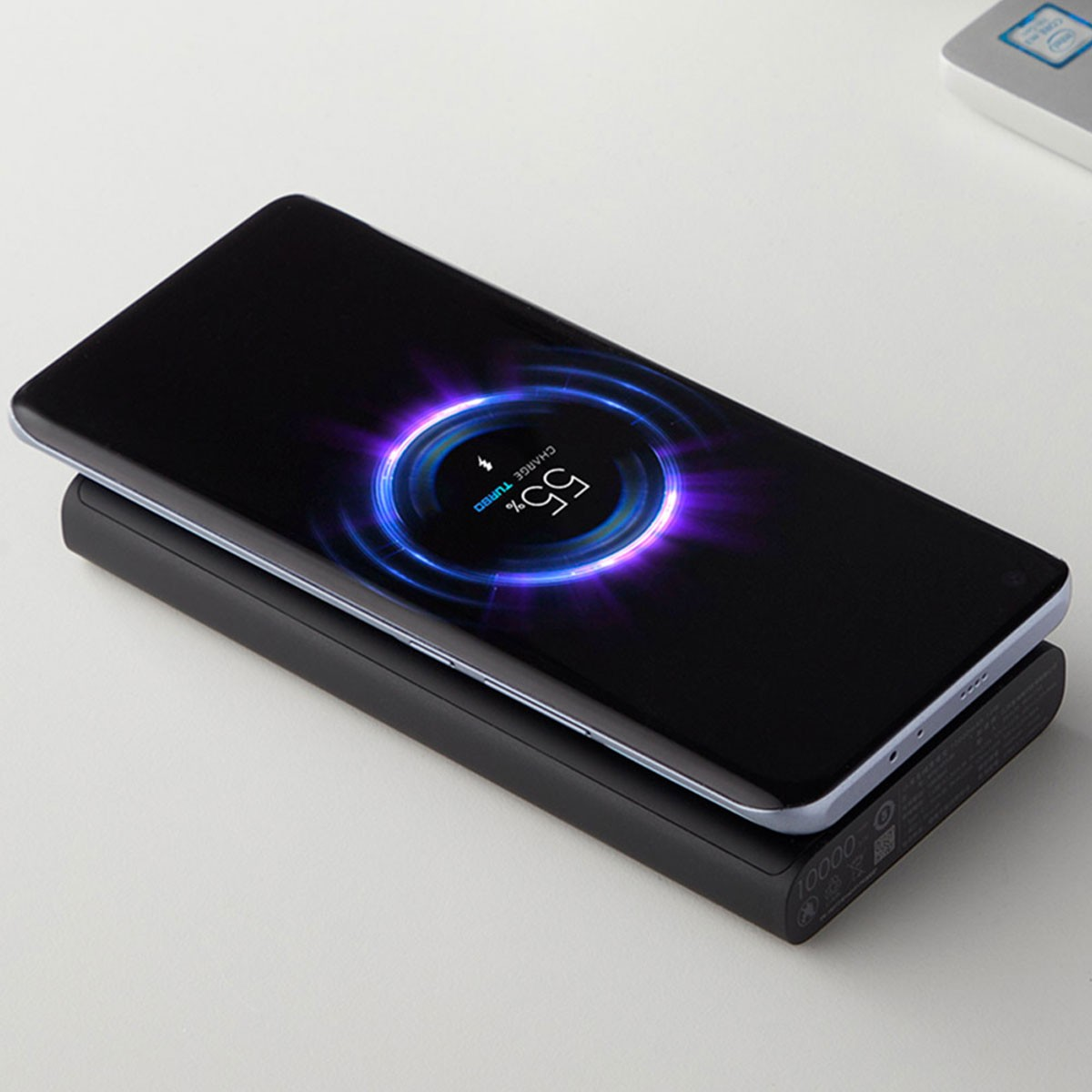 Telefono in carica su un power bank nero. Lo schermo mostra un'animazione di ricarica. Sfondo bianco.