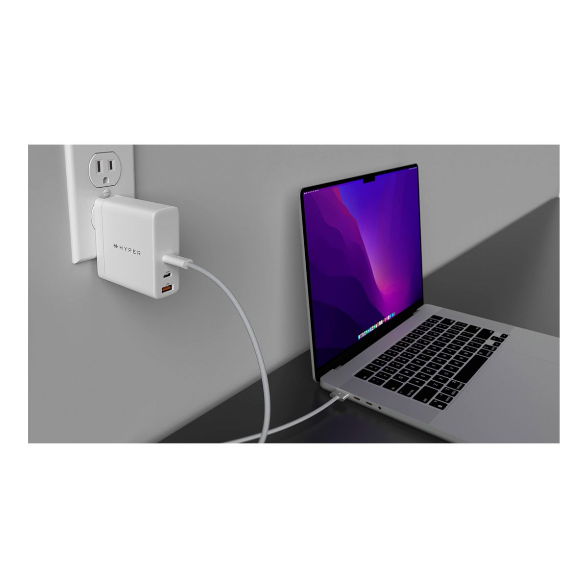 Un adaptador de corriente blanco conectado a una laptop y a un enchufe de pared.