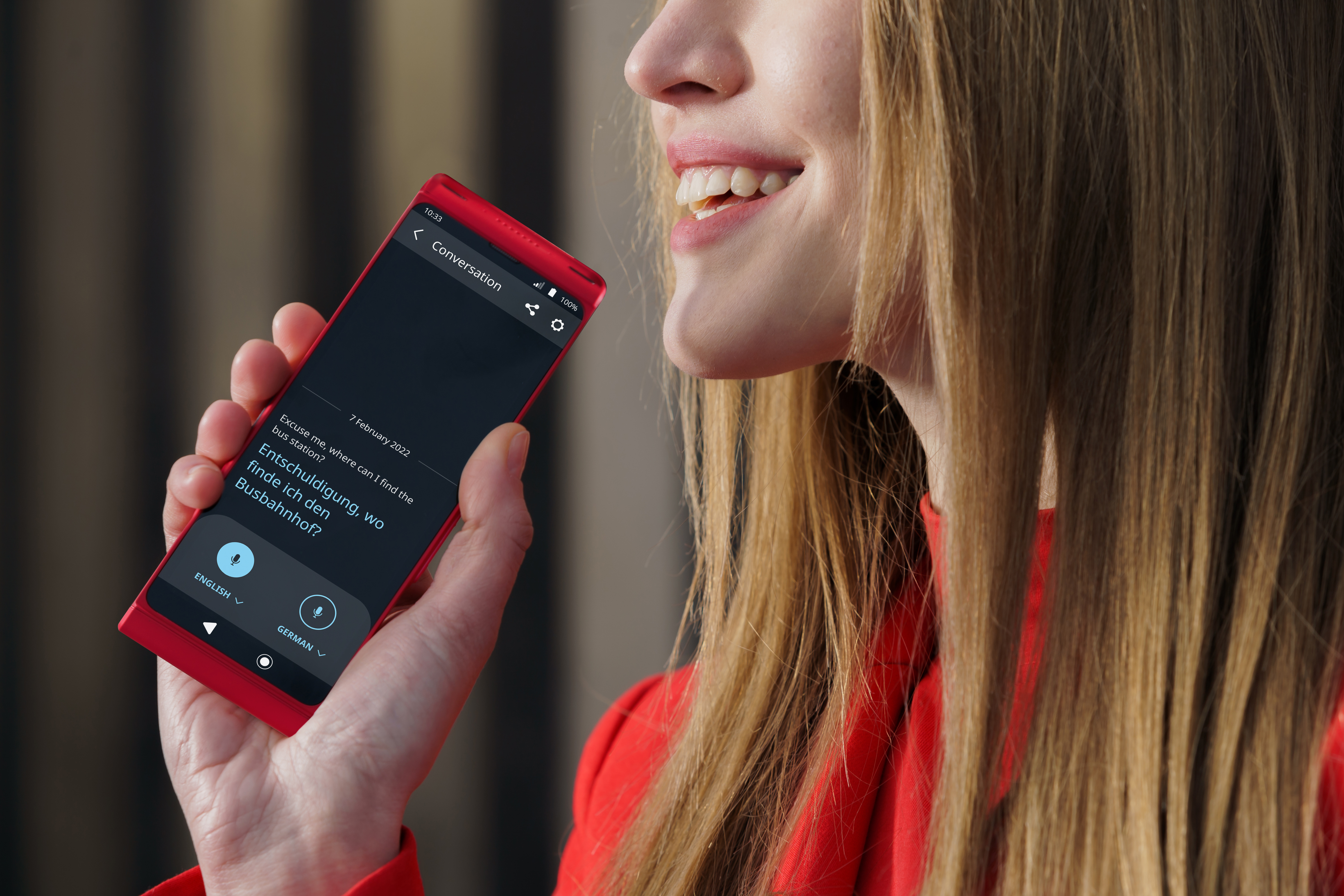 Eine Frau hält ein rotes Telefon mit einer Übersetzungs-App.