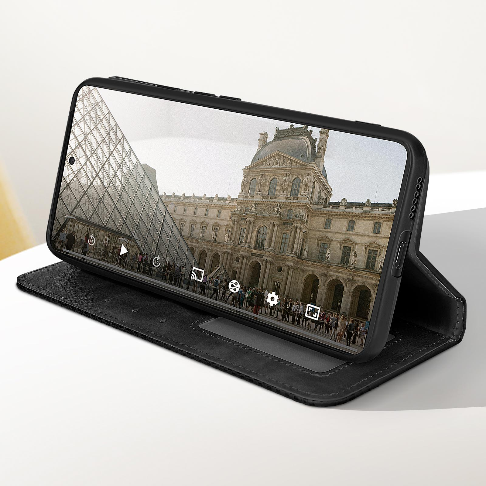 Telefono in custodia nera mostra edificio con piramide. La custodia è aperta su superficie bianca.