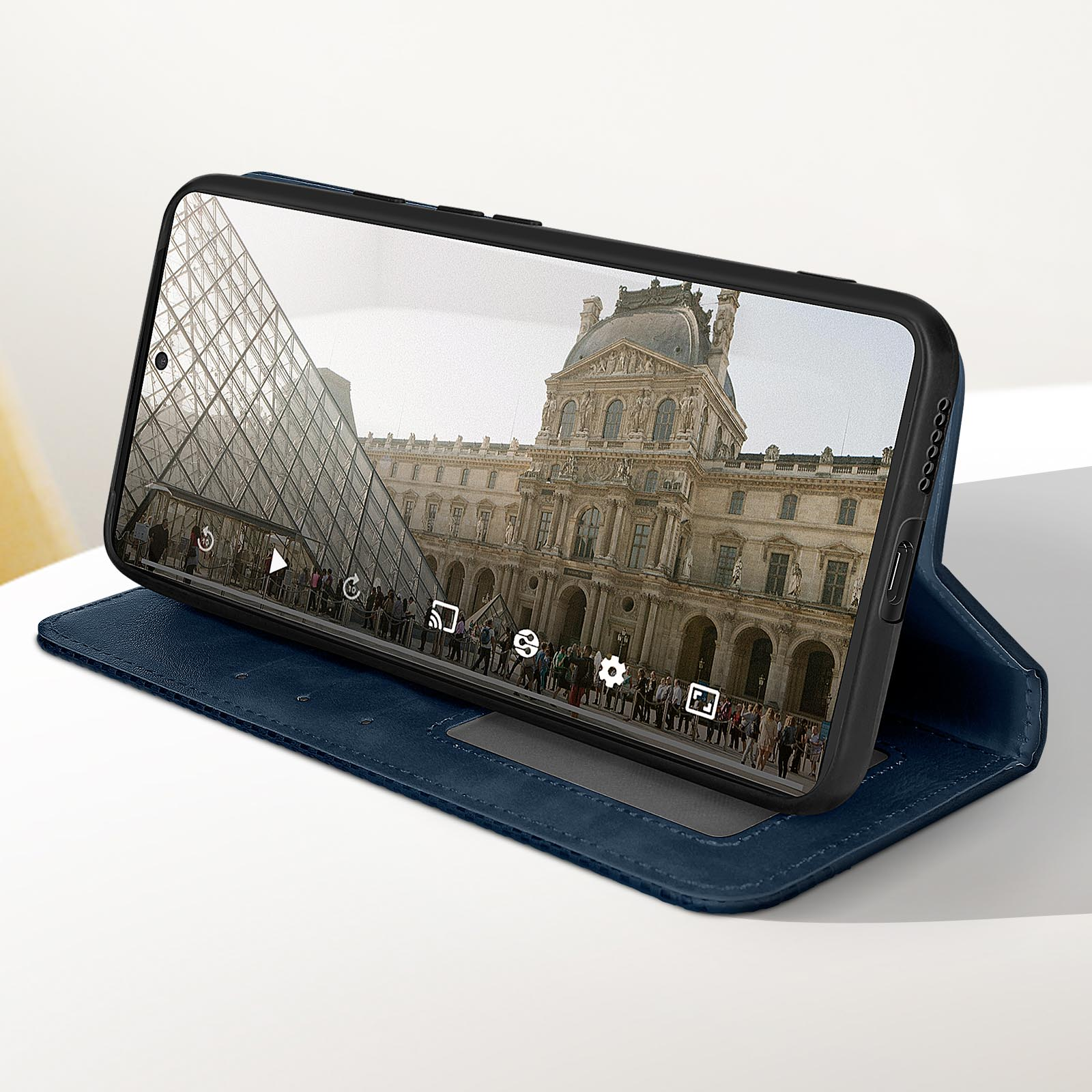 Uno smartphone mostra una foto del Museo del Louvre, aperto in una custodia di pelle blu.