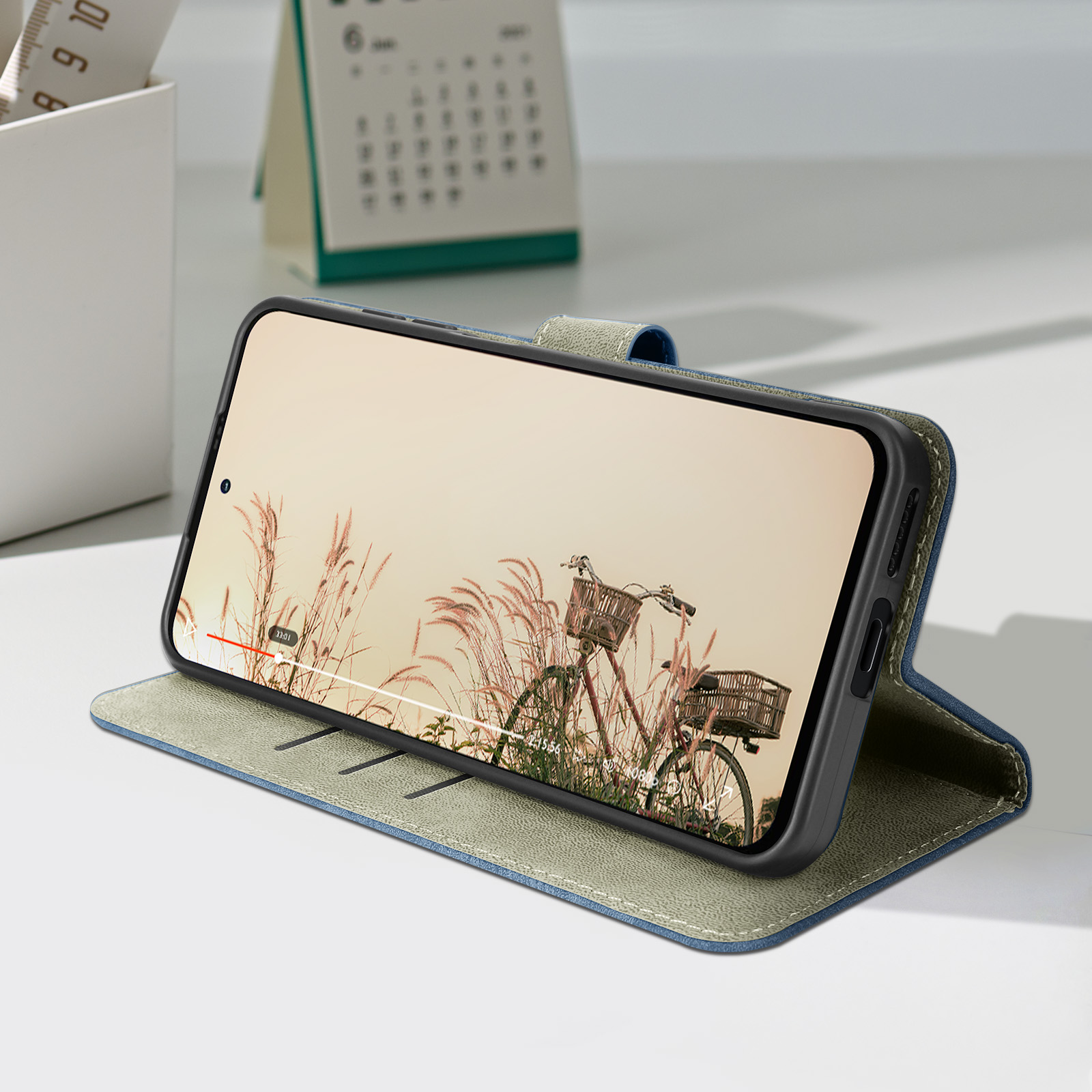 Telefono in una custodia, aperto, su un tavolo. Un calendario e un portapenne sono sullo sfondo.