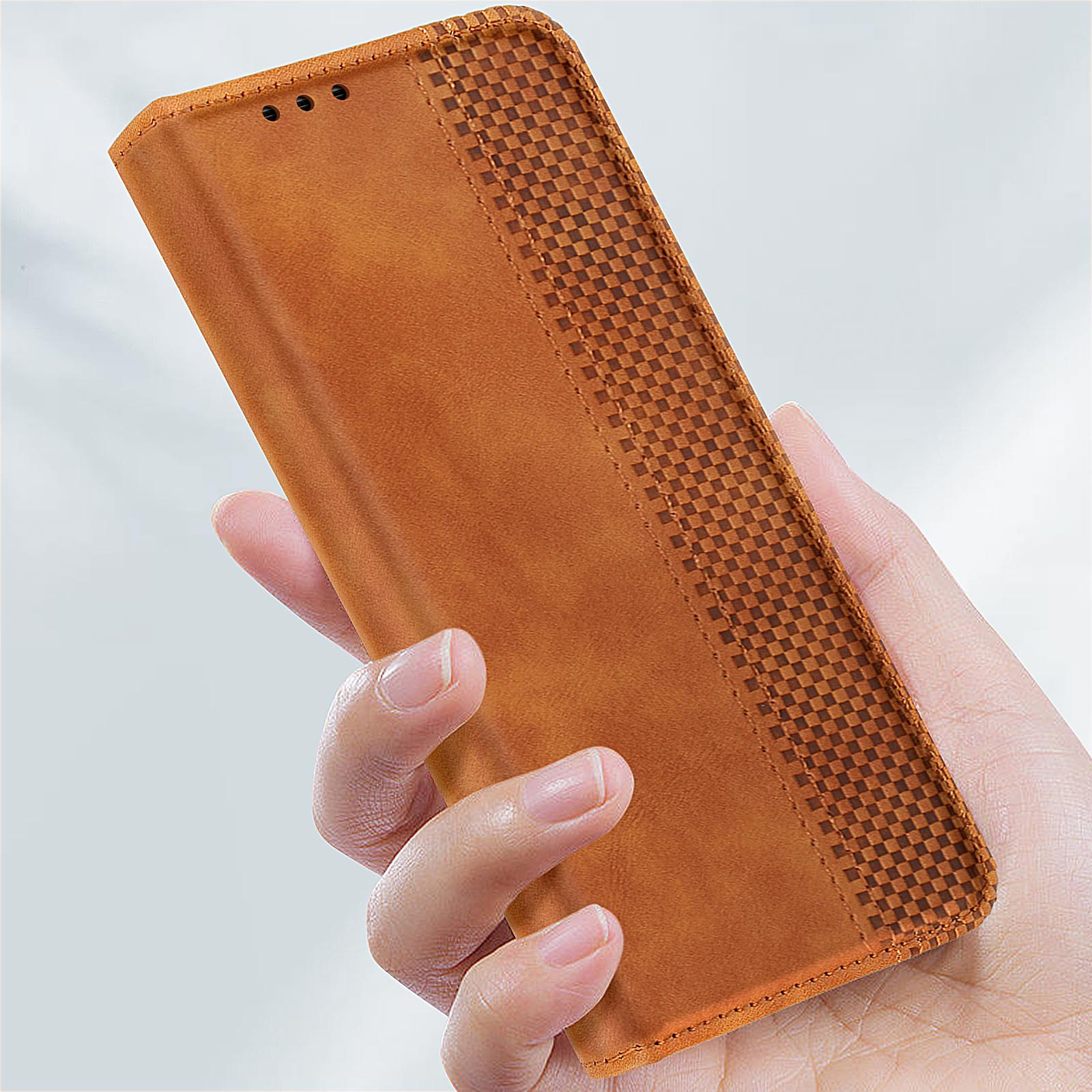 Una mano che tiene una custodia per telefono in pelle marrone con un motivo a quadri e un design a portafoglio.