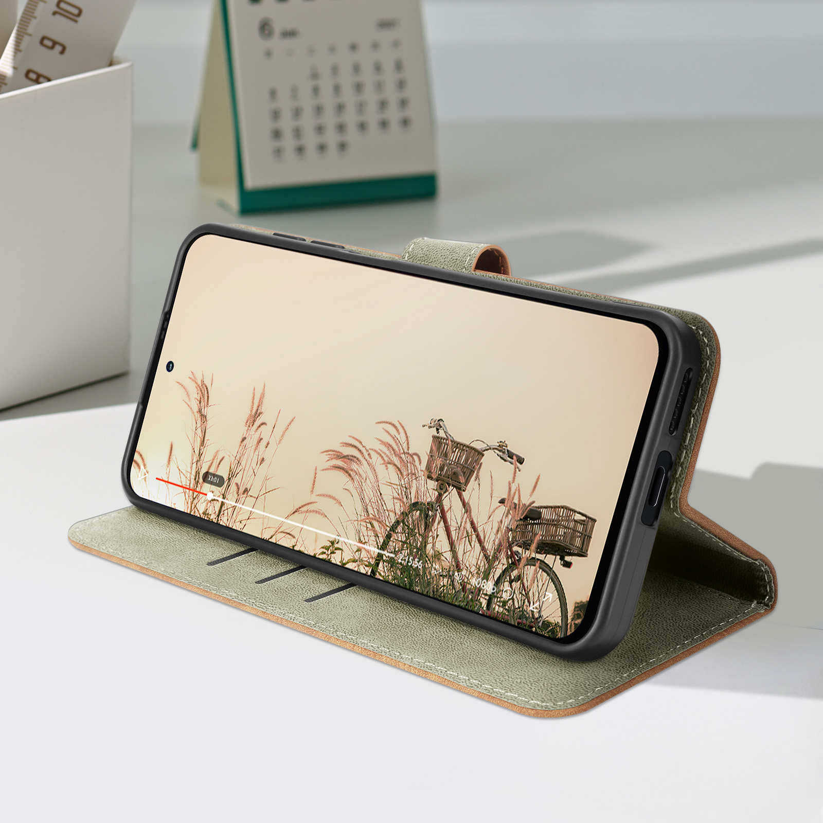 Un telefono in una custodia di pelle verde è appoggiato, mostrando una scena di bicicletta sullo schermo.