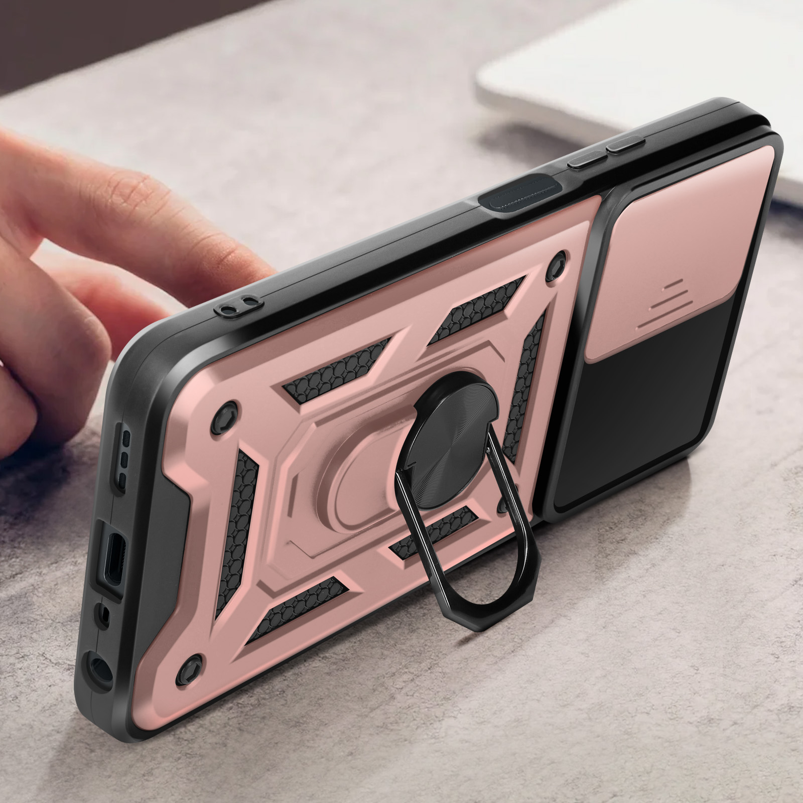 Primo piano di una custodia per telefono con supporto ad anello. Schema colori rosa e nero. Una mano tocca il telefono.