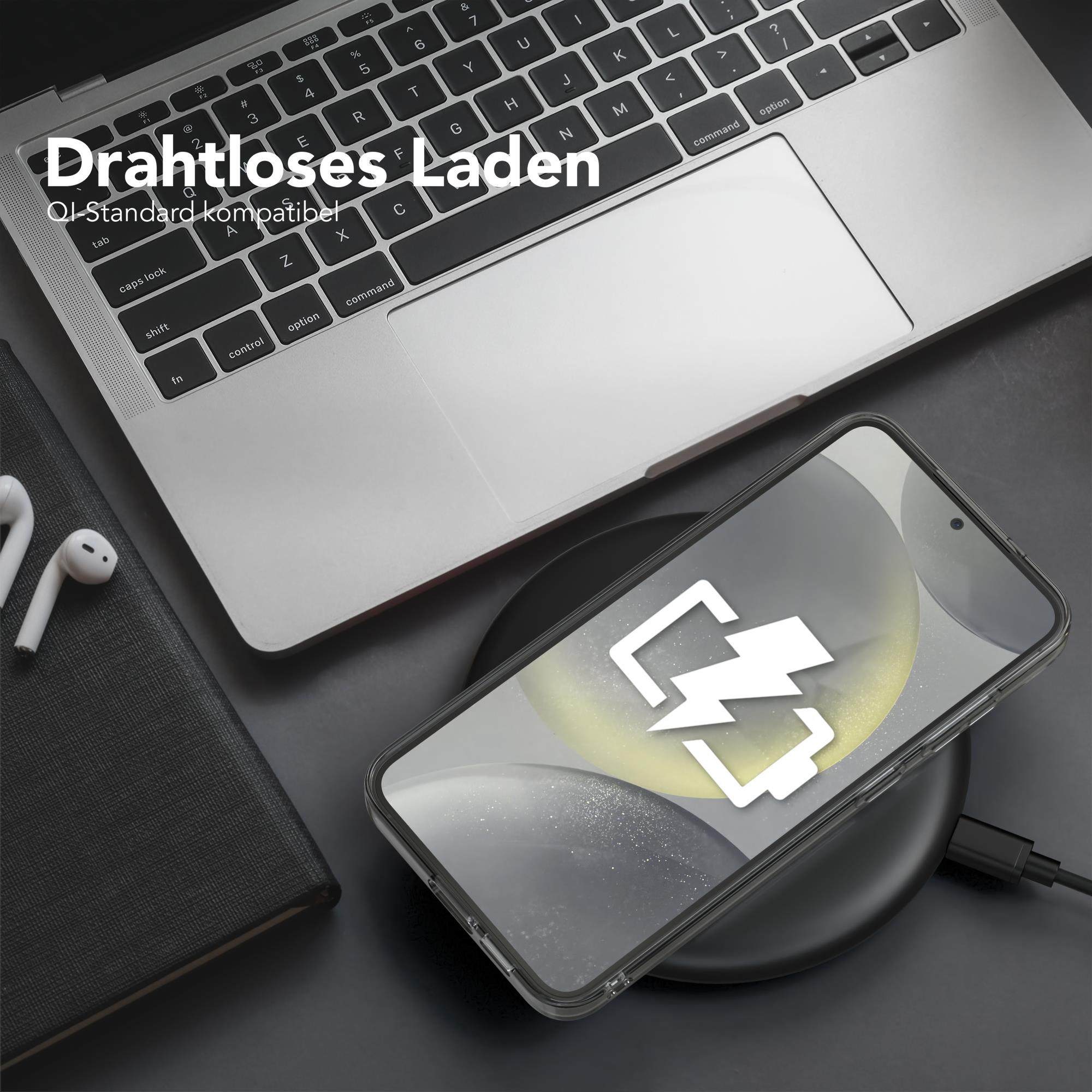 Ein Telefon auf einem kabellosen Ladegerät mit Laptop und Kopfhörern neben einem schwarzen Notizbuch.
