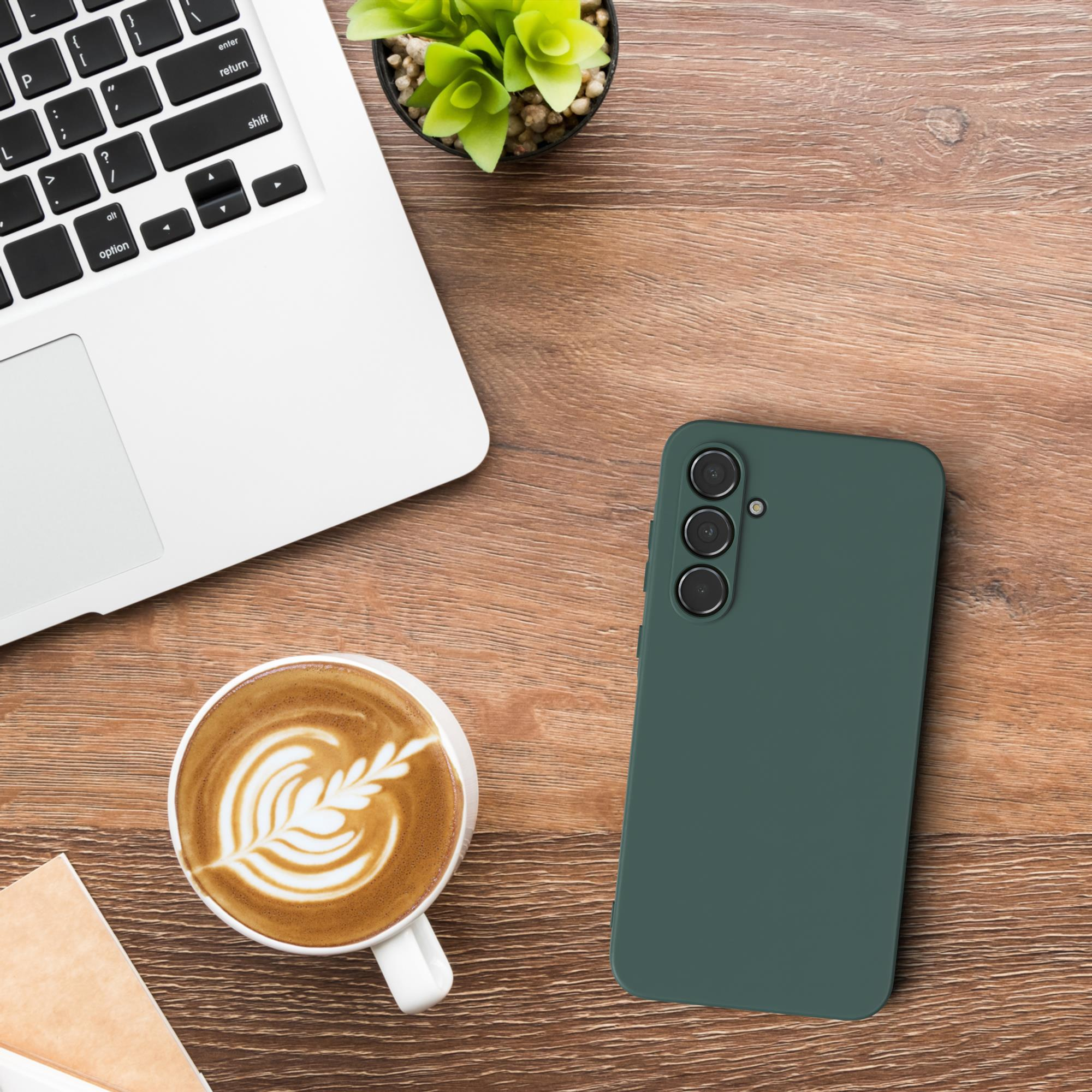 Laptop, Telefon und eine Tasse Kaffee auf einem Holztisch, grüne Handyhülle.
