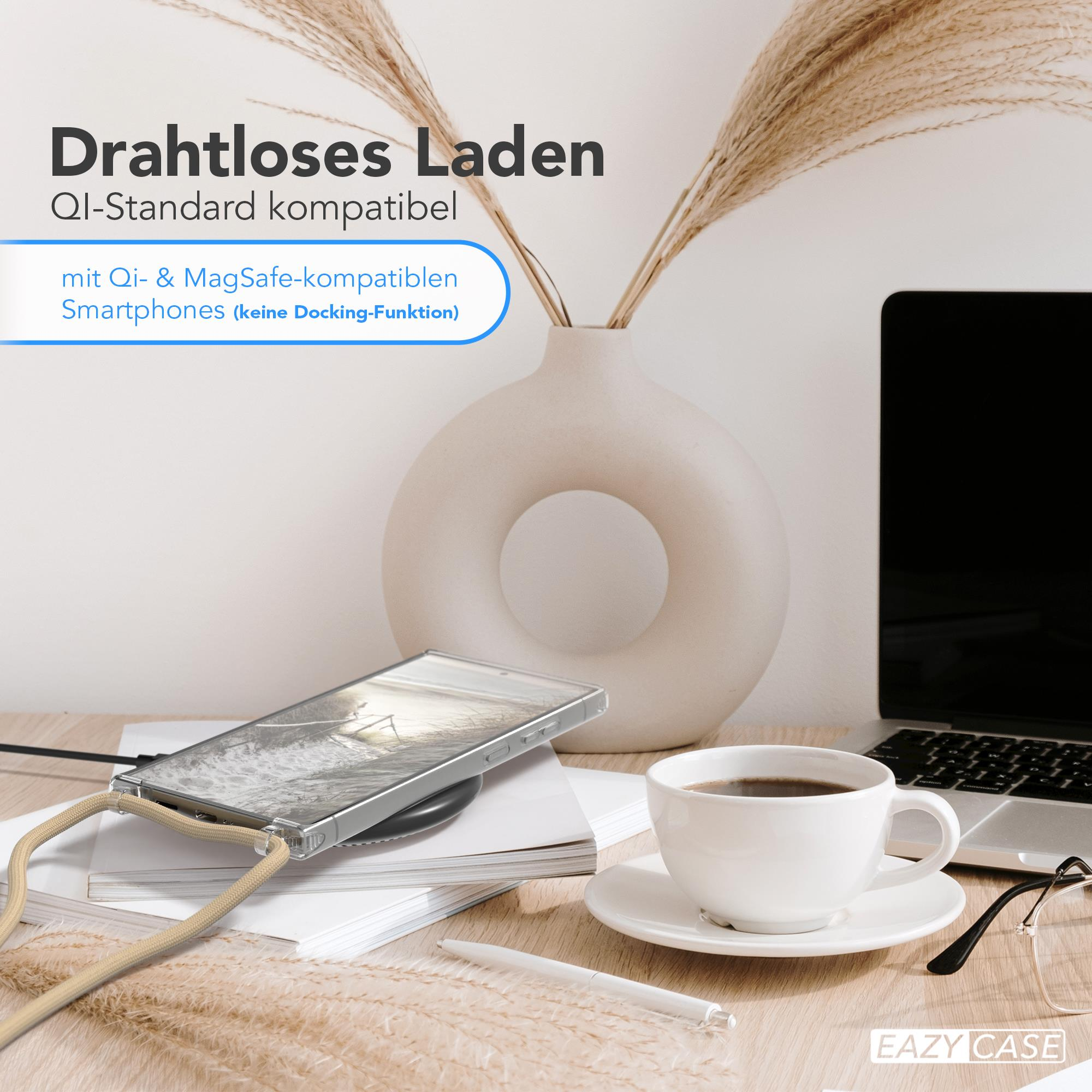 Ein Telefon, das drahtlos auf einem Pad neben einem Laptop und einer Kaffeetasse geladen wird.