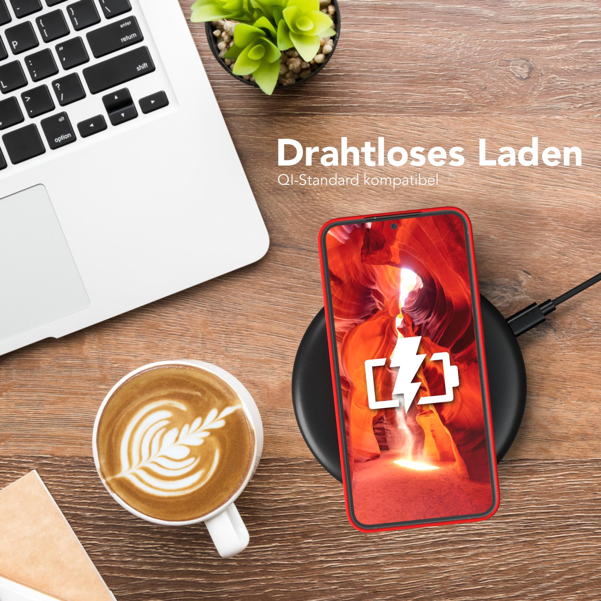 Ein Telefon auf einem kabellosen Ladegerät mit einer Kaffeetasse und einem Laptop in der Nähe.