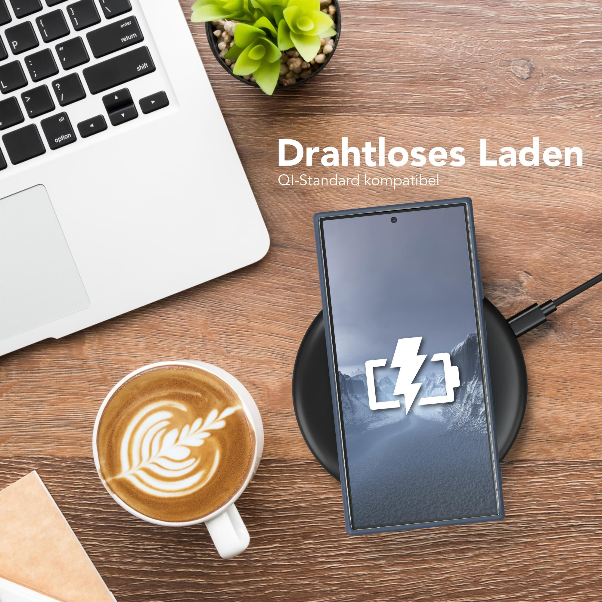 Telefon wird kabellos auf einem Pad geladen. Kaffee und Laptop stehen auf dem Tisch.