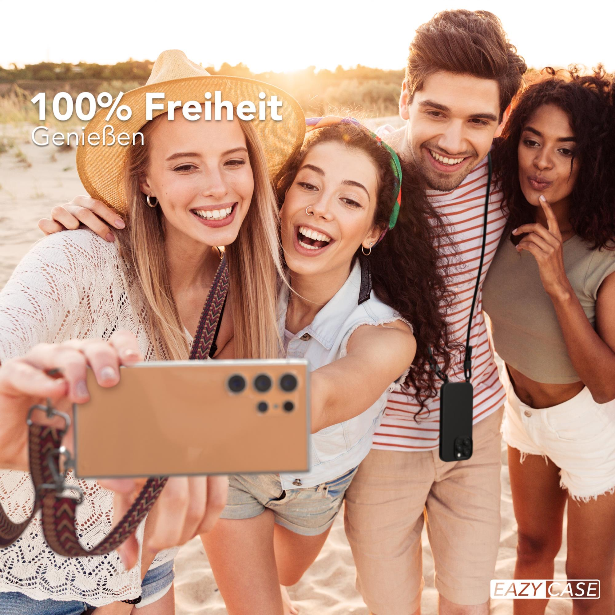Vier Personen machen ein Selfie am Strand, eine hält ein Telefon und genießt den Tag.