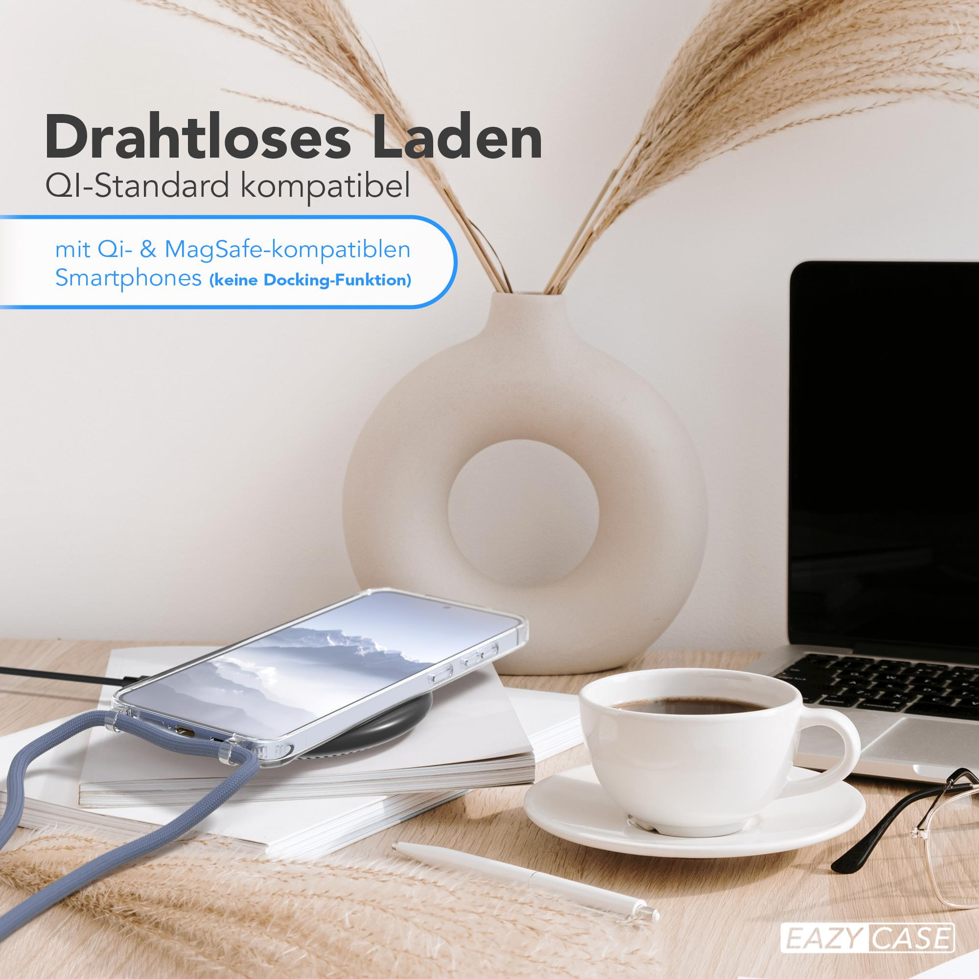 Ein Smartphone, das auf einem kabellosen Ladepad auf einem Schreibtisch geladen wird, mit Vase und Tasse.