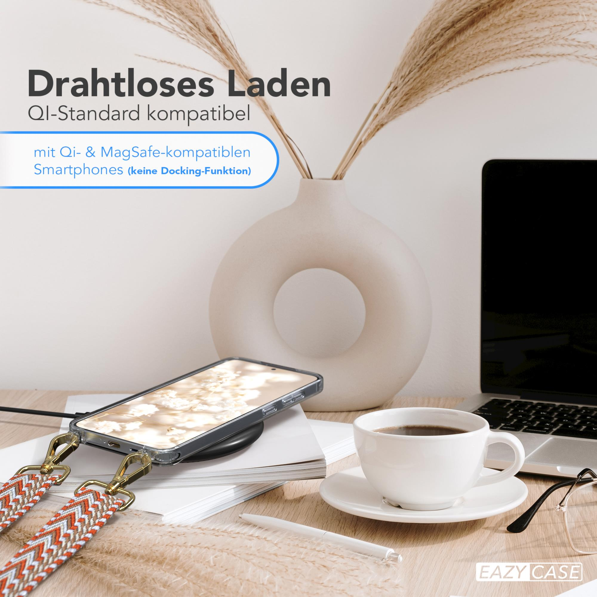 Telefon, das auf einem kabellosen Ladegerät geladen wird. Auf einem Tisch stehen eine Kaffeetasse, eine Vase mit Pflanzen und Gläser.