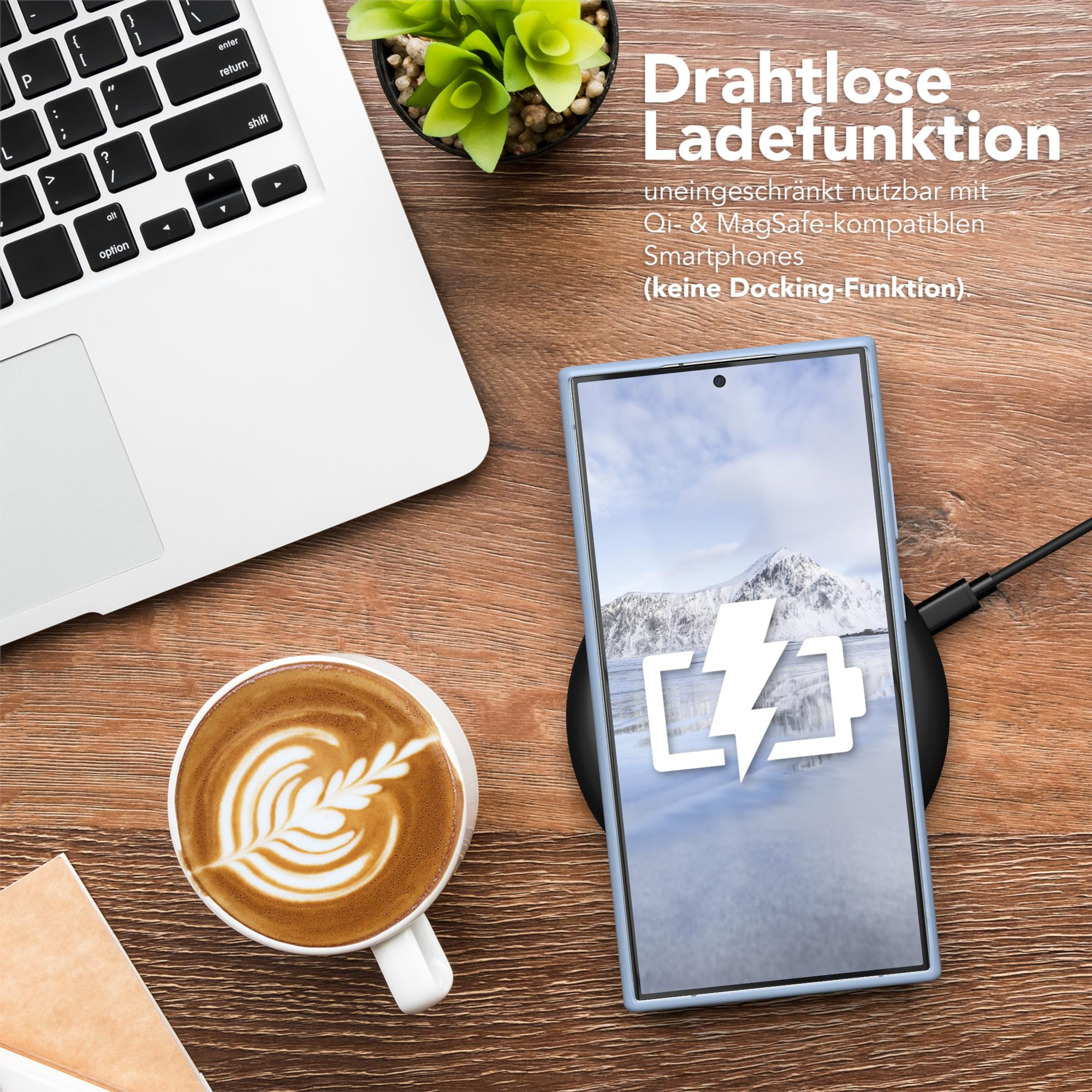 Ein Laptop, ein Telefon, das auf einem kabellosen Ladegerät aufgeladen wird, und eine Kaffeetasse auf einem Holztisch.