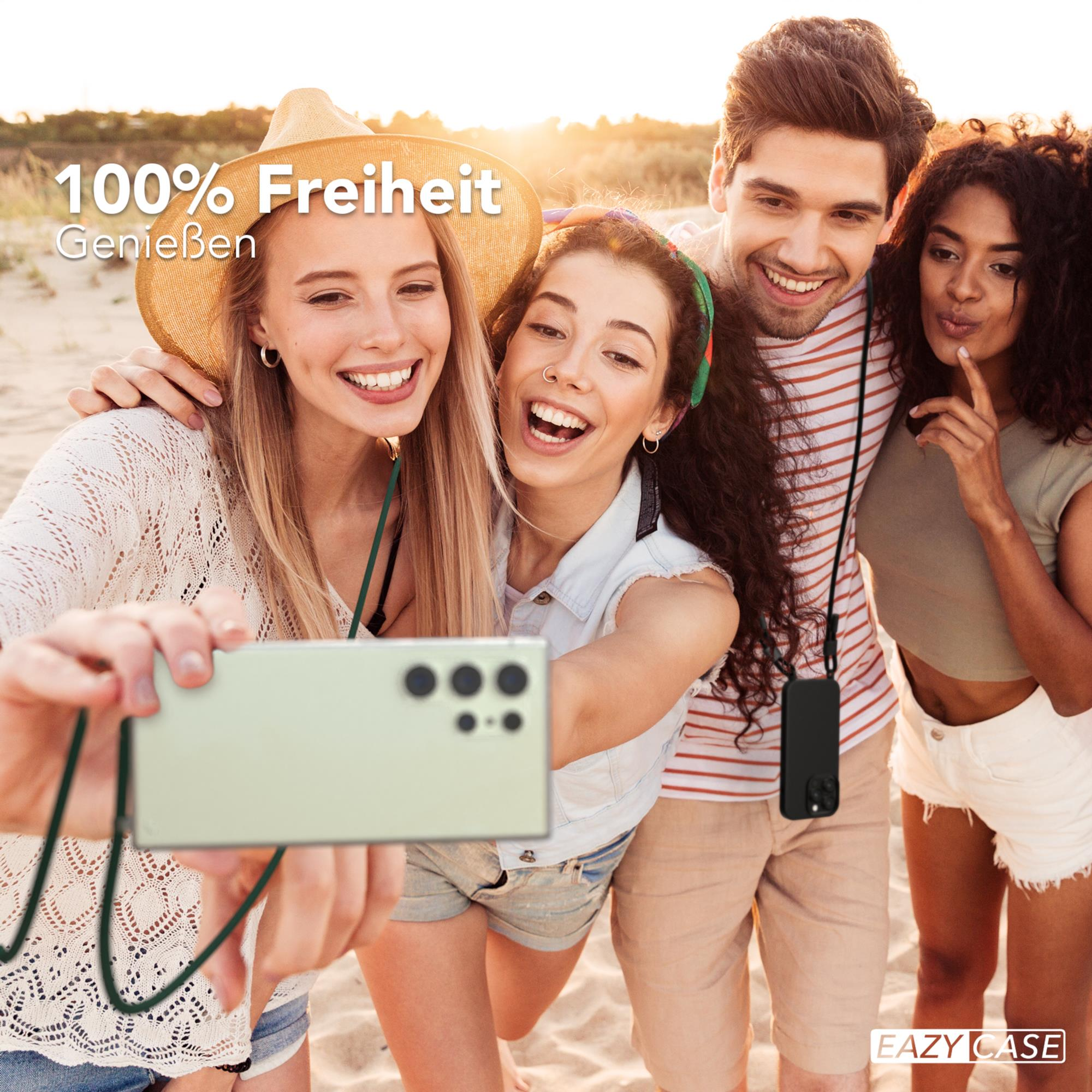 Gruppe von Freunden macht ein Selfie am Strand. Eine Person hält ein Telefon mit einem Schlüsselband.