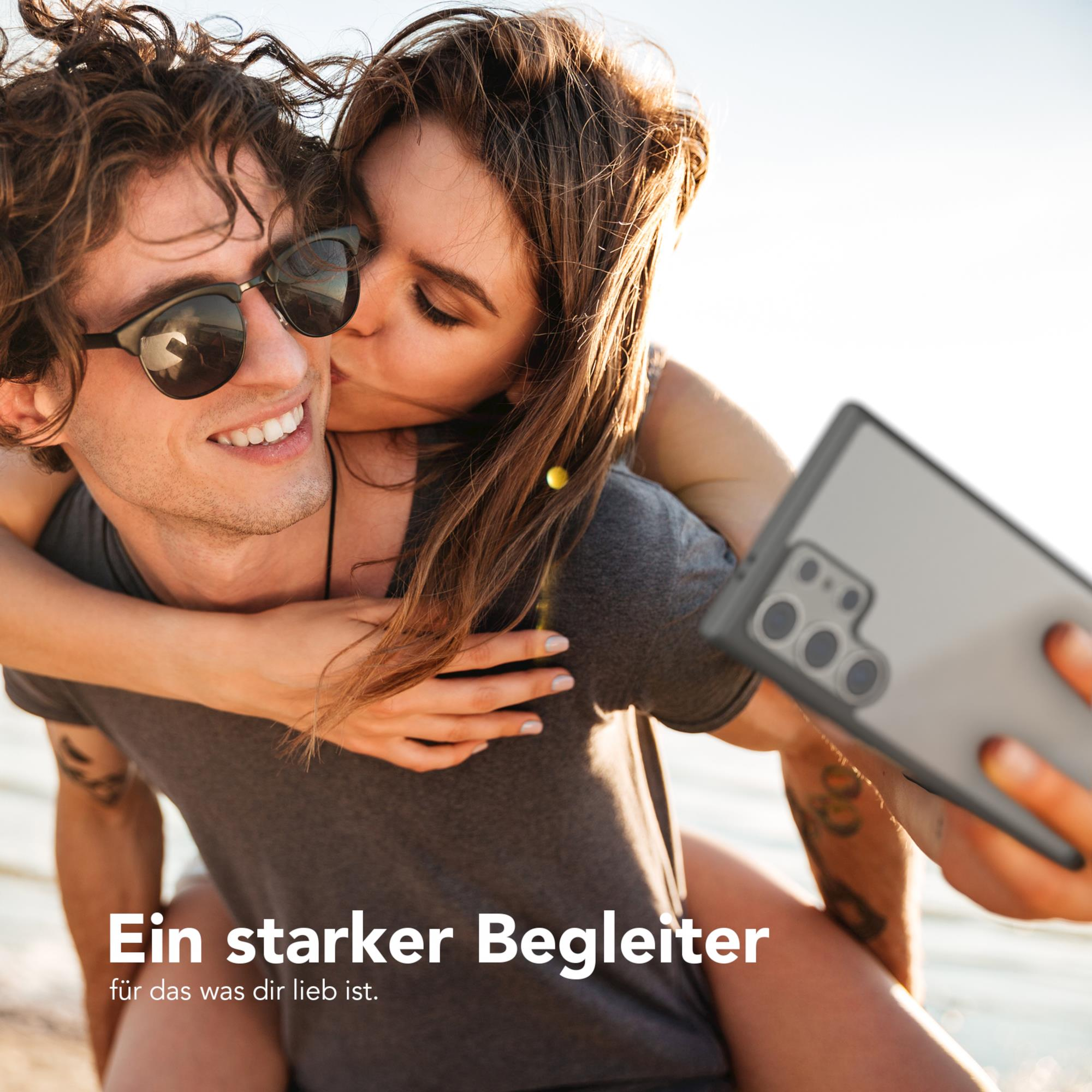 Paar macht Selfie mit Handyhülle. Text: 'Ein starker Begleiter', verschwommener Hintergrund.